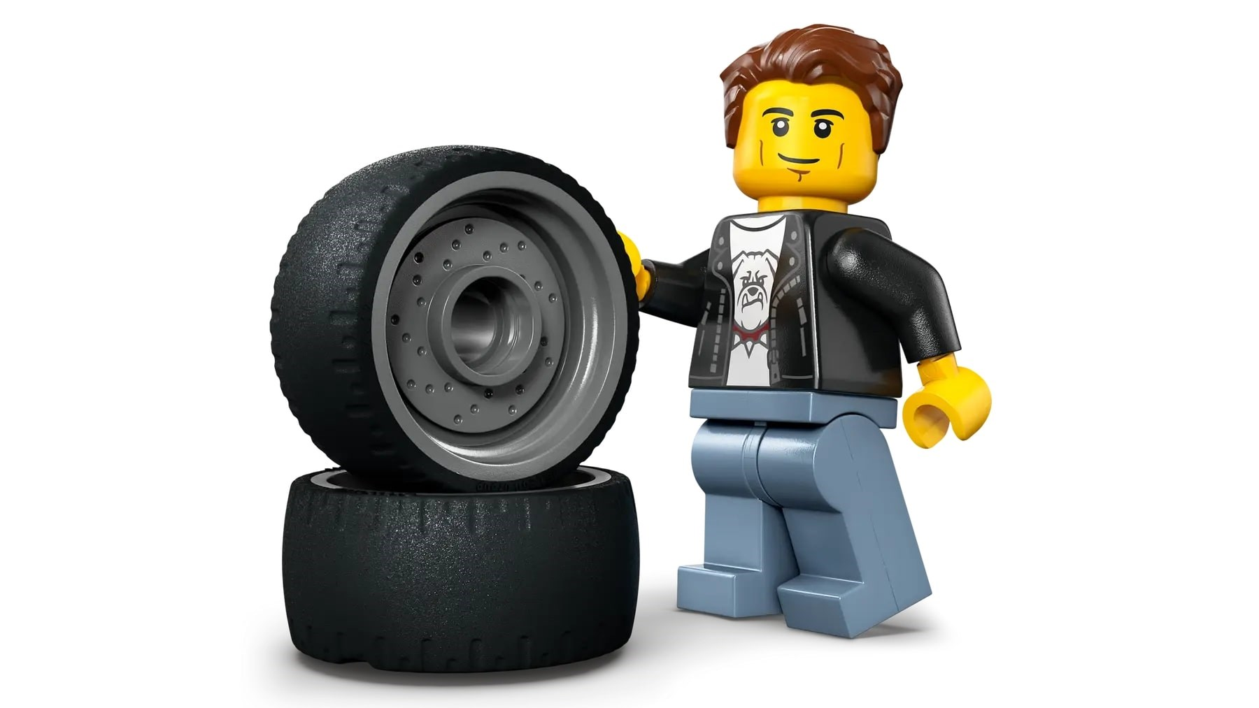 Figurka Lego z brązowymi włosami i żółtą skórą stoi obok dwóch opon. Figurka ma na sobie czarną kurtkę i niebieskie spodnie.