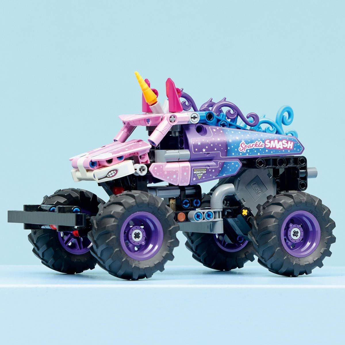Kolorowa zabawka Lego w postaci monster trucka. Ma duże koła, róg jednorożca i napis 'Sparkle Smash' na niebieskim tle.