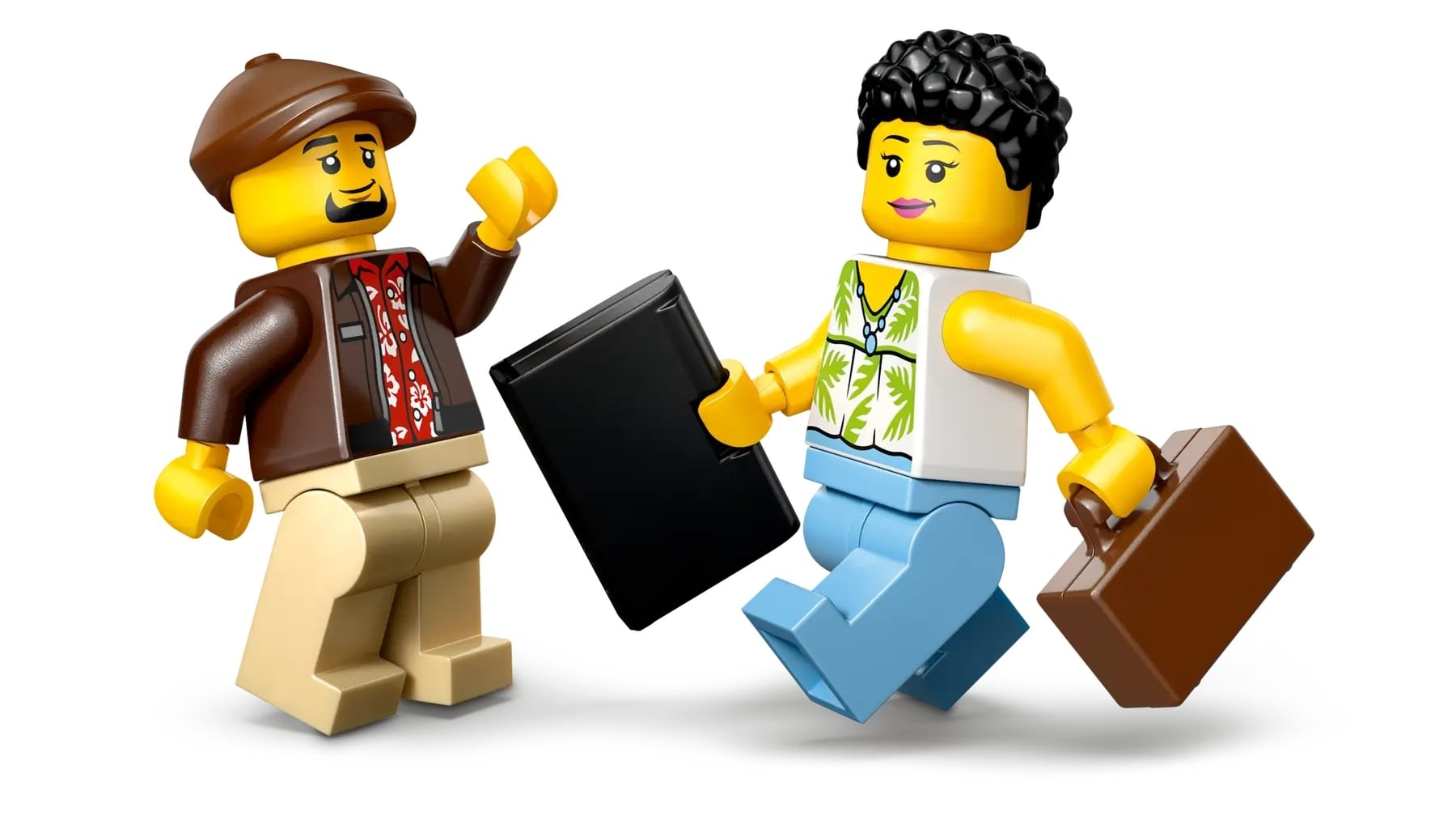 Dwie figurki Lego: jedna w czapce i kurtce, druga w kwiecistej koszuli i walizce. Jedna trzyma czarny przedmiot.