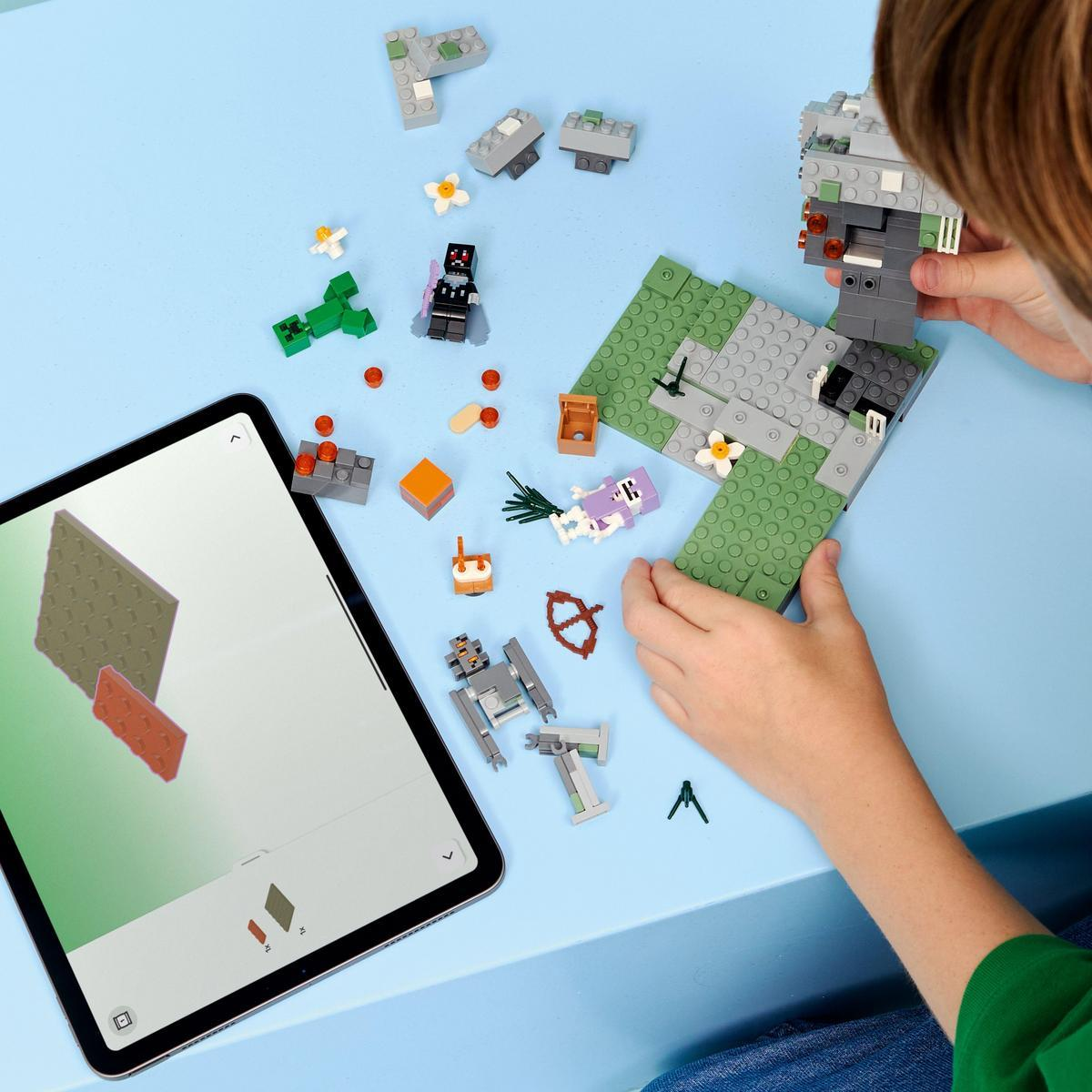 Dziecko buduje z klocków Lego na niebieskim stole. Jest tablet pokazujący model i różne rozrzucone klocki Lego.