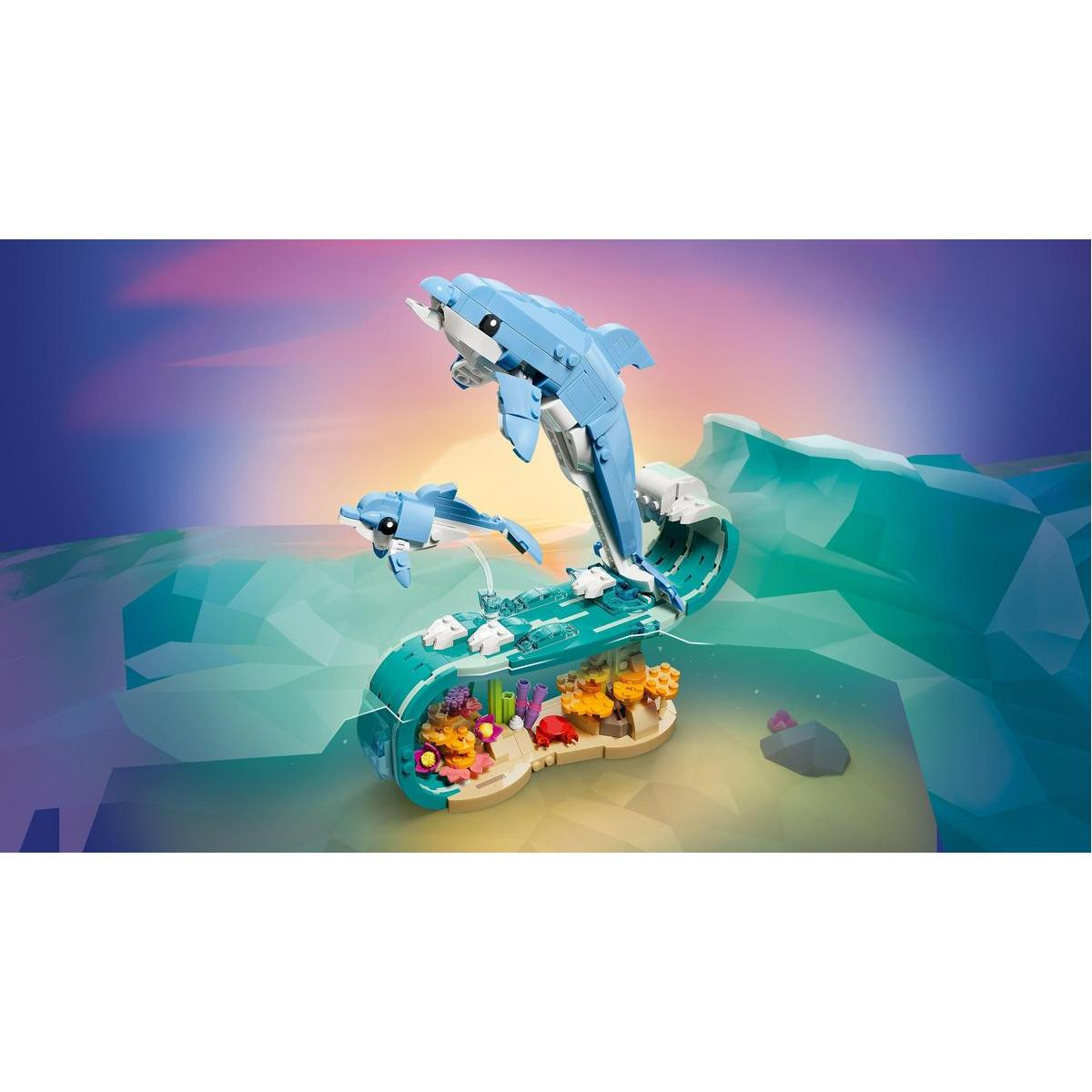 Zestaw Lego przedstawia dwa niebieskie delfiny skaczące nad falą. W tle scena morska z koralowcami i skałą.