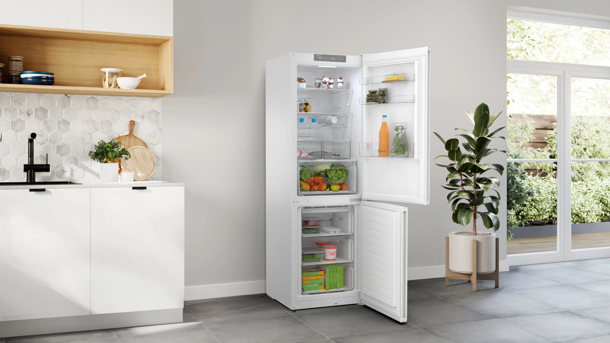 Refrigerador abierto en una cocina. Se ven verduras, frutas y bebidas. Una gran planta está junto a una ventana.