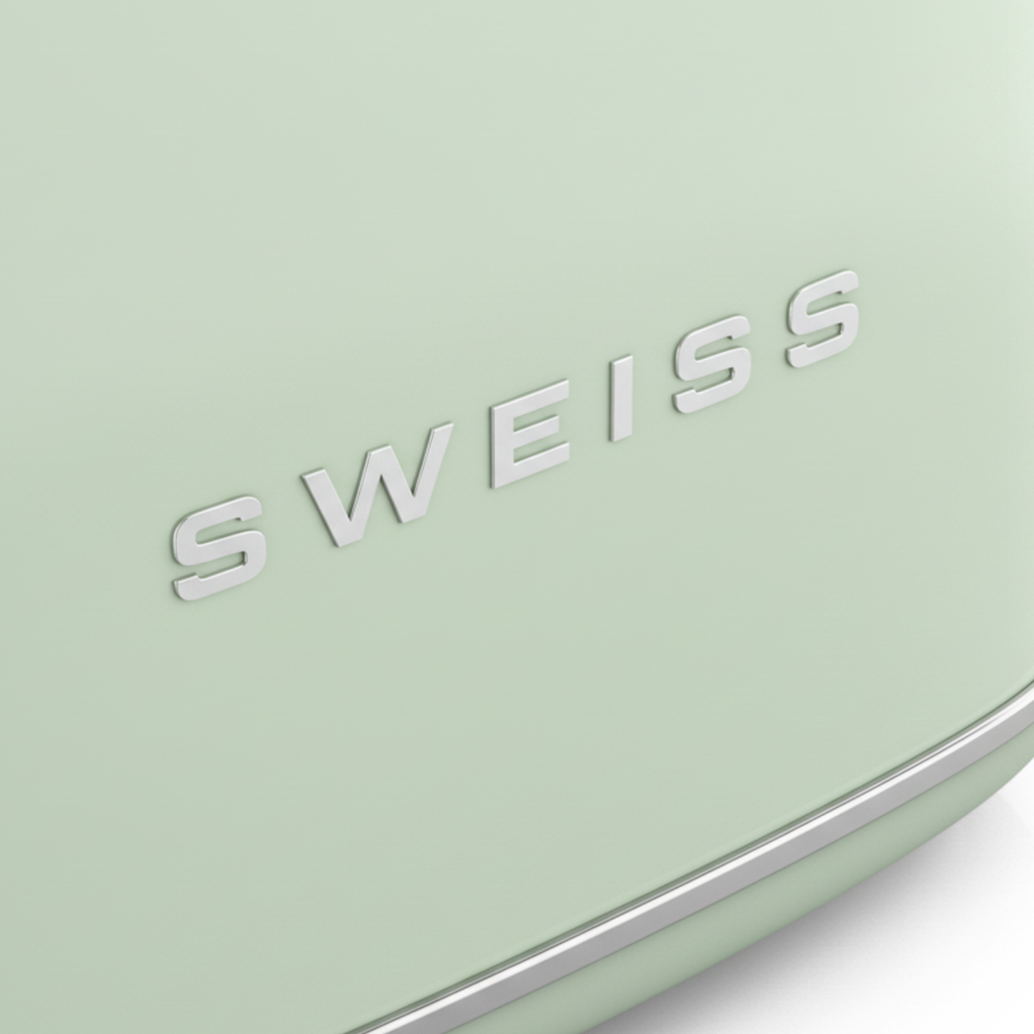 Nahaufnahme eines mintgrünen Geräts mit dem Wort 'WEISS' in silbernen Buchstaben. Ein Chrombesatz säumt die Unterkante.