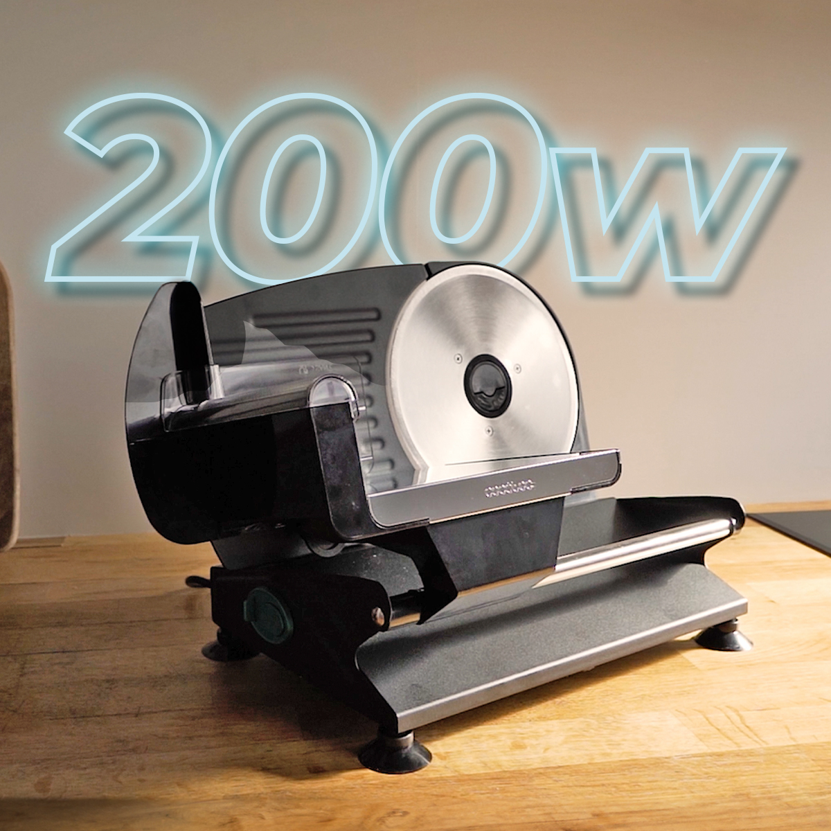 Czarna i srebrna krajalnica do żywności na drewnianej powierzchni. W tle napis "200W".