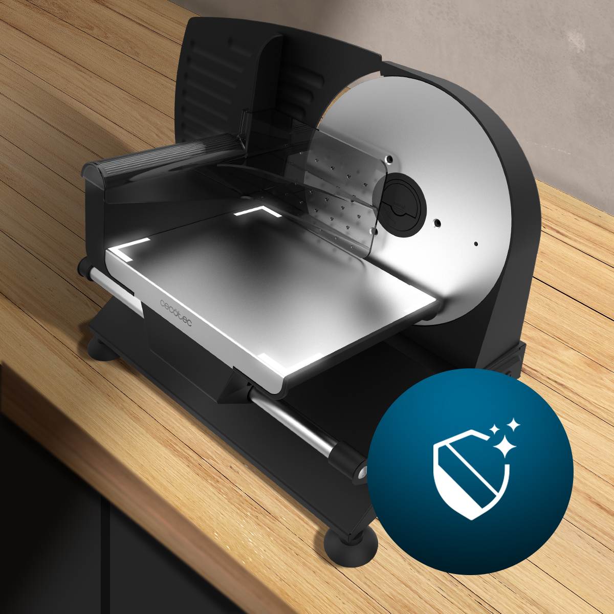 Czarna i srebrna krajalnica do mięsa na drewnianej powierzchni. Niebieska ikona tarczy w prawym dolnym rogu.