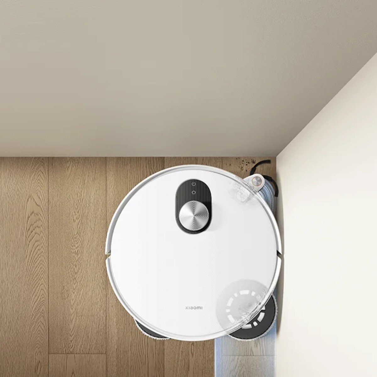 Biały robot odkurzający na drewnianej podłodze. Jest blisko białej ściany. Odkurzacz ma czarną górę z przyciskami.