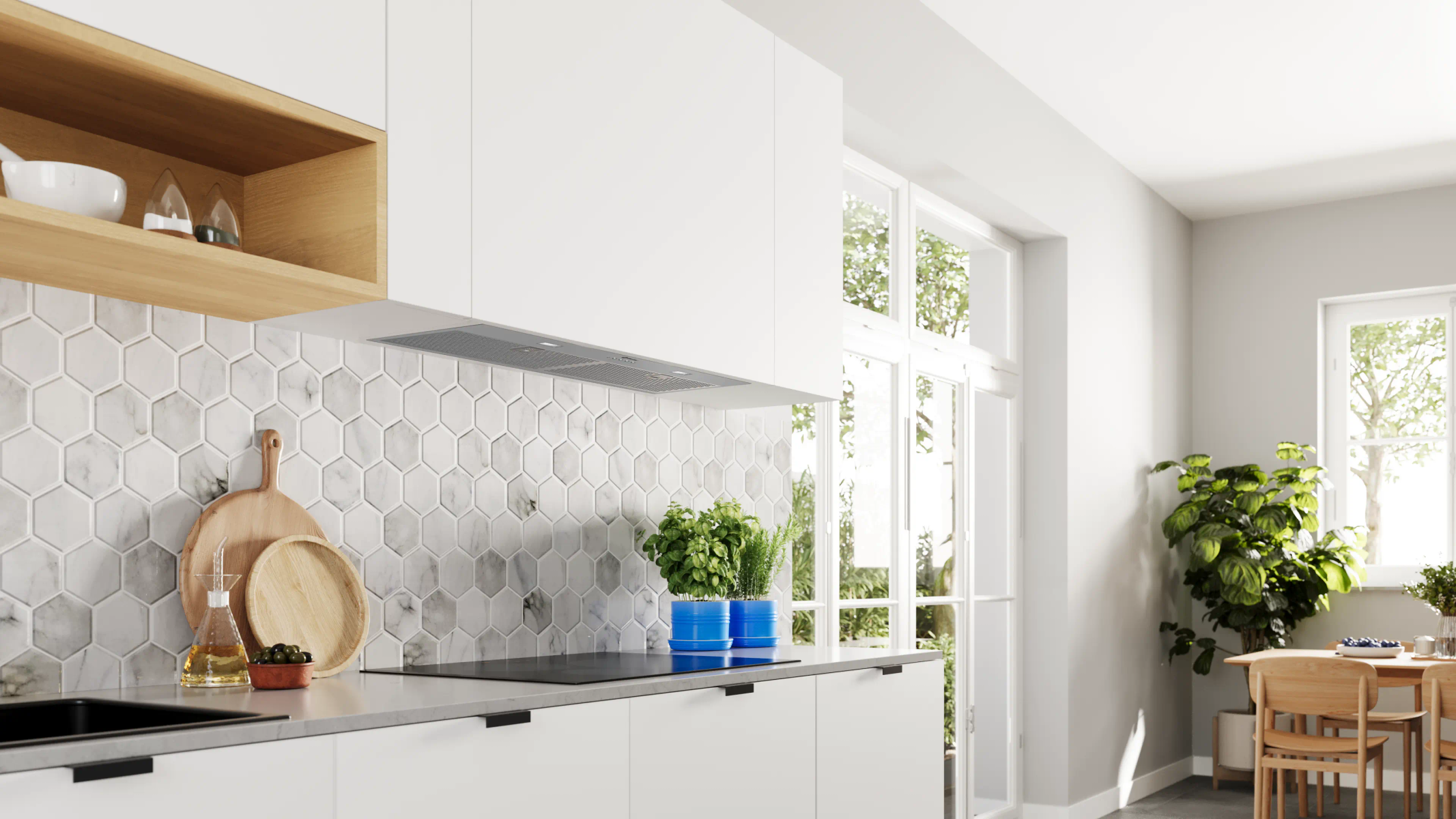 Cucina moderna con mobili bianchi, alzatina in marmo e finestra. Include piante, taglieri in legno e tavolo da pranzo.