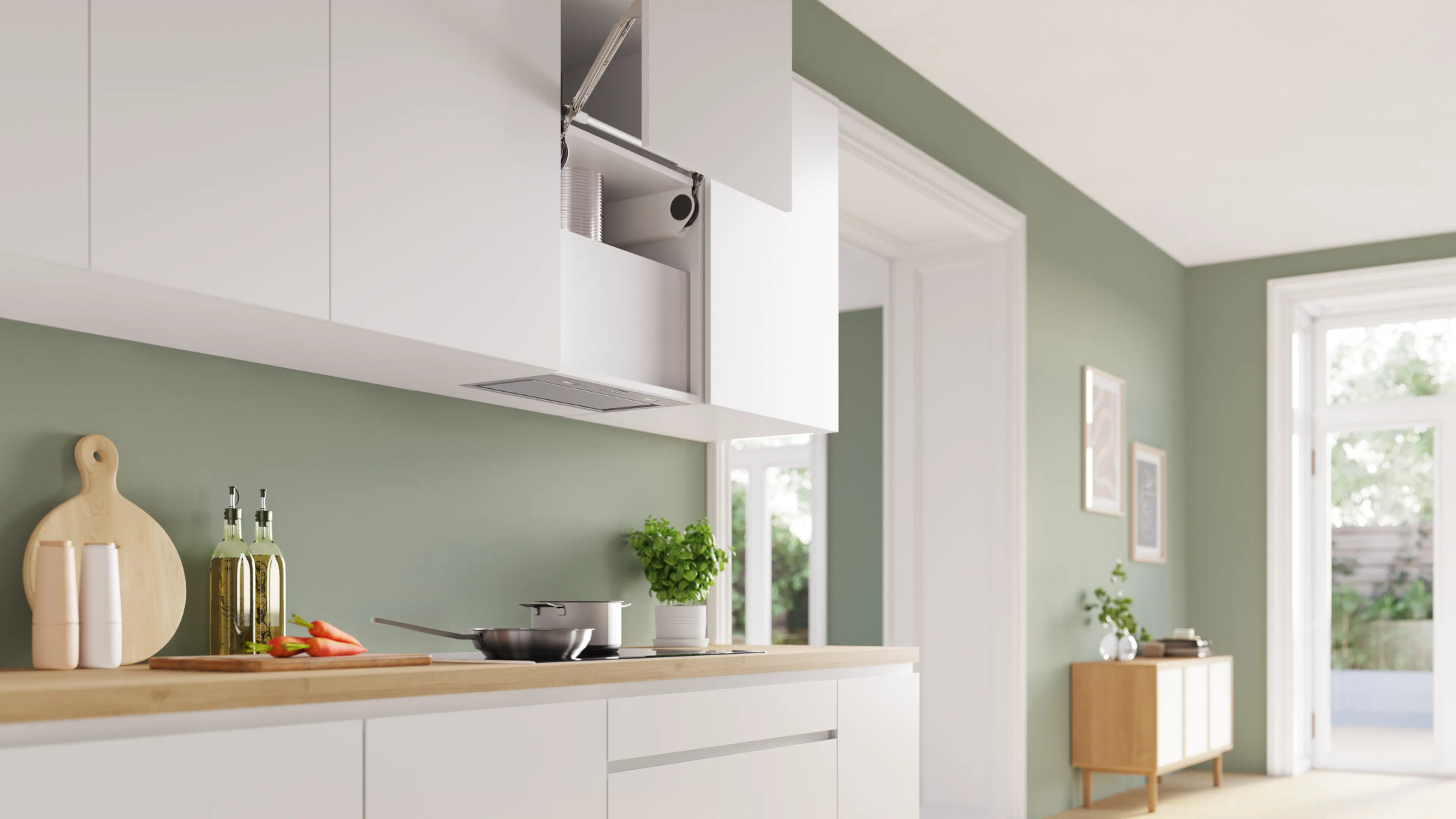 Cucina moderna con mobili bianchi, piano di lavoro in legno, utensili da cucina, carote e parete verde.