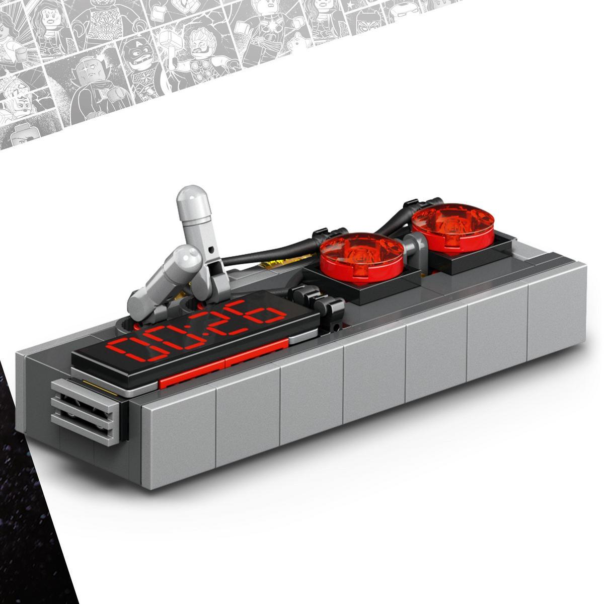 Szare urządzenie podobne do Lego z wyświetlaczem "00:26" i dwoma czerwonymi światłami. Srebrne ramię po lewej.