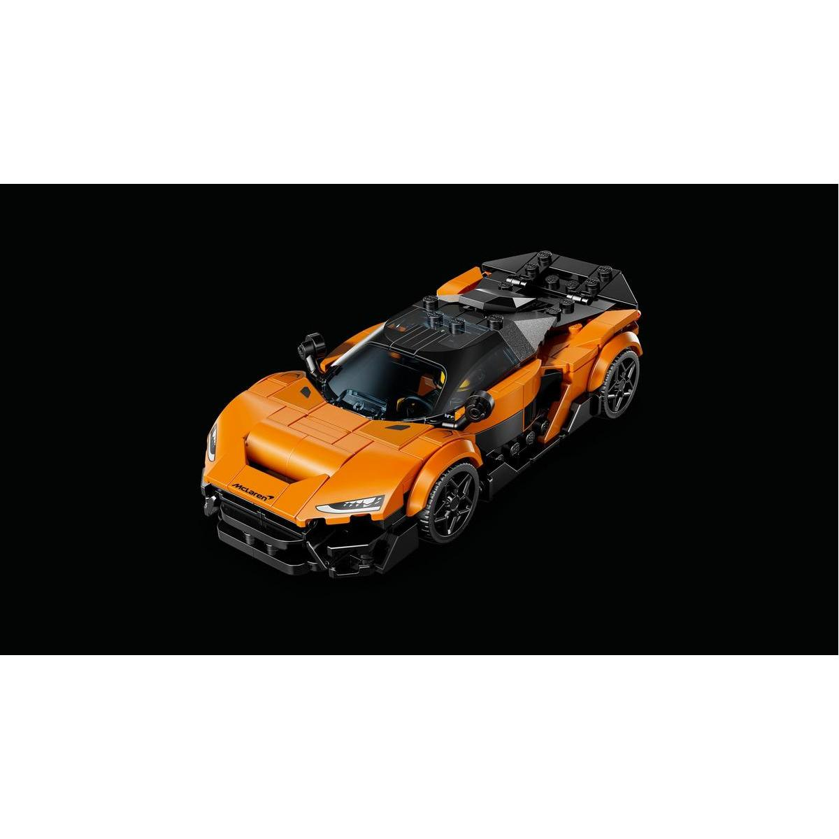 Pomarańczowy samochód sportowy Lego McLaren Senna z czarnymi akcentami na czarnym tle. Samochód jest lekko pochylony.