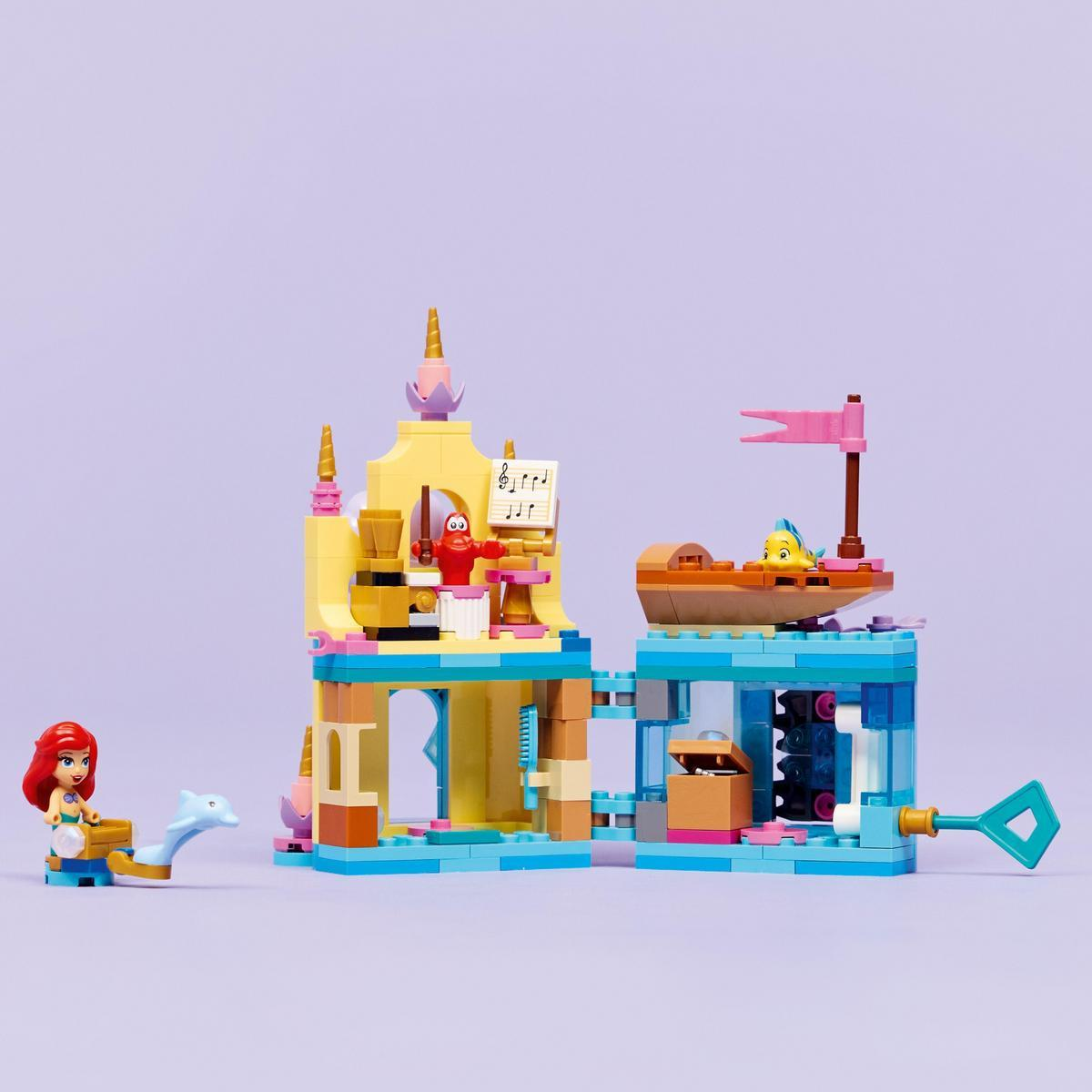 Un set de Lego con Ariel, Flounder en un barco, un castillo y otros elementos marinos. Sobre un fondo morado.