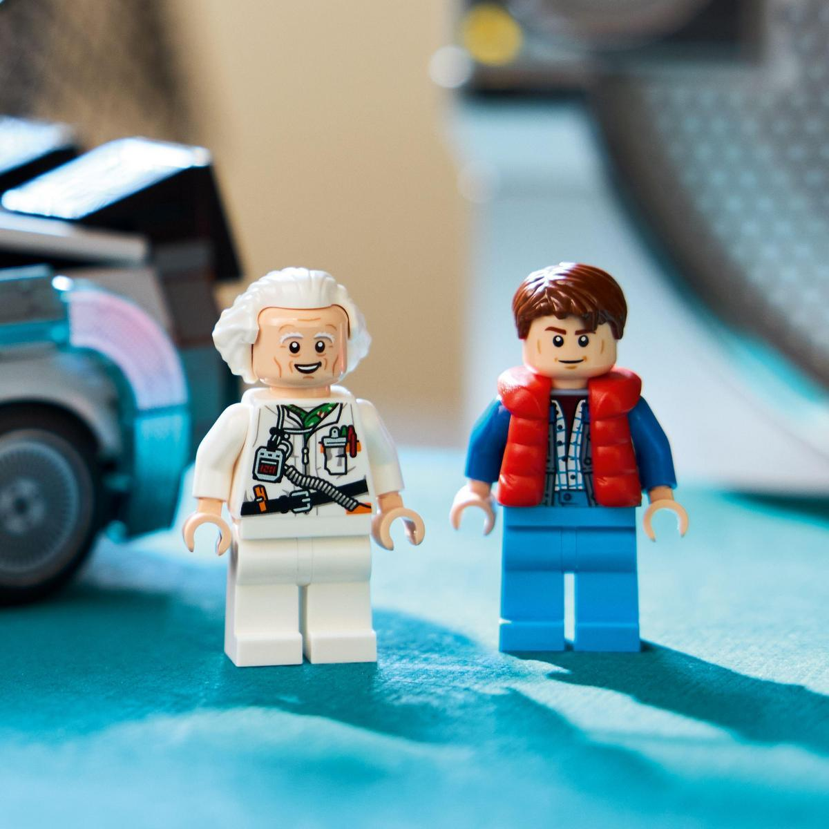 Dwie figurki Lego Doktora Browna i Marty'ego McFly z Powrotu do przyszłości stoją przed DeLoreanem. Niebieskie tło.