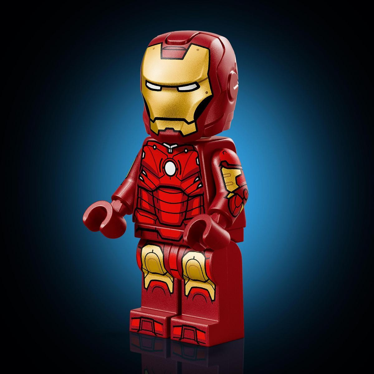 Bir Lego Iron Man figürü ayakta duruyor, kırmızı zırh, maske, omuzlar ve dizlerde altın detaylar. Mavi degrade arka plan.