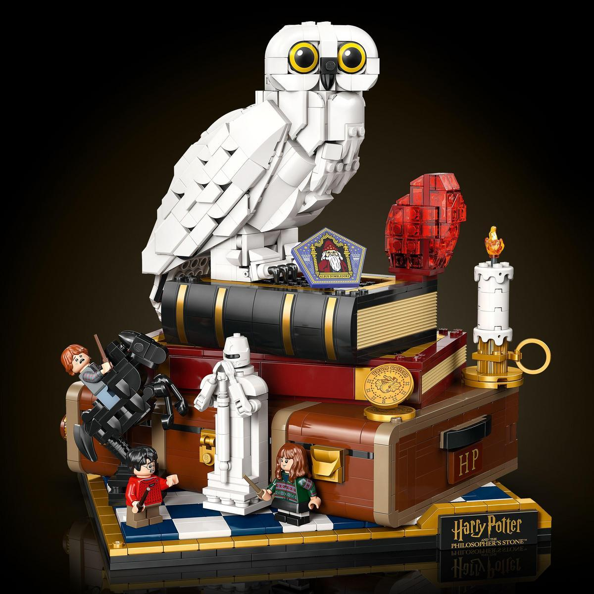 Zestaw Lego Harry Potter. Biała sowa siedzi na książkach. Obecne są figurki Lego Harry'ego, Rona i Hermiony oraz inne elementy.