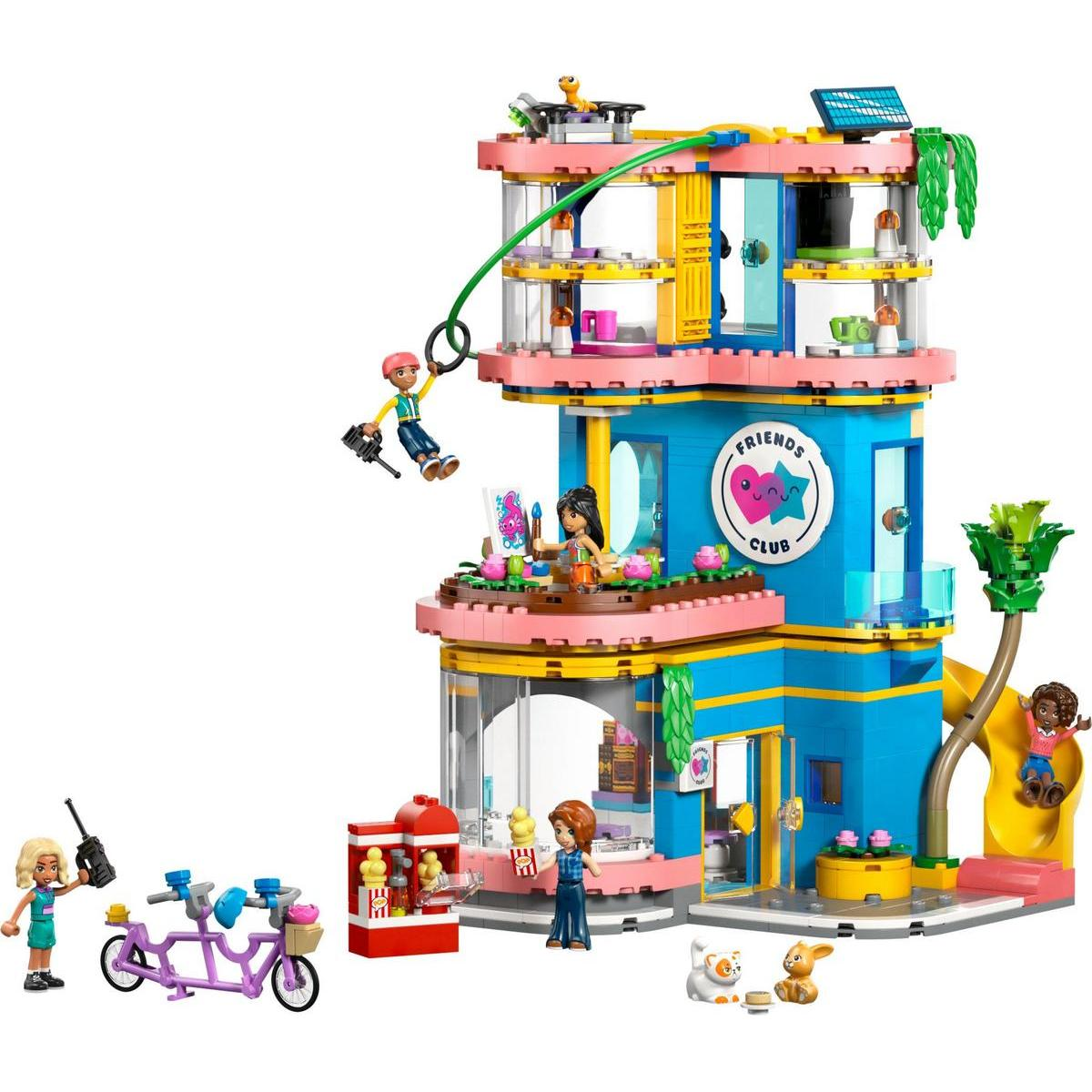 Un edificio LEGO Friends Club colorato con personaggi, teleferica, scivolo e accessori, tra cui bicicletta e bancarella di popcorn.