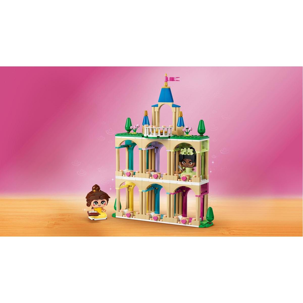 Zamek Lego z dwiema figurkami. Dziewczyna w żółtej sukience stoi z przodu. Inna dziewczyna jest w oknie.