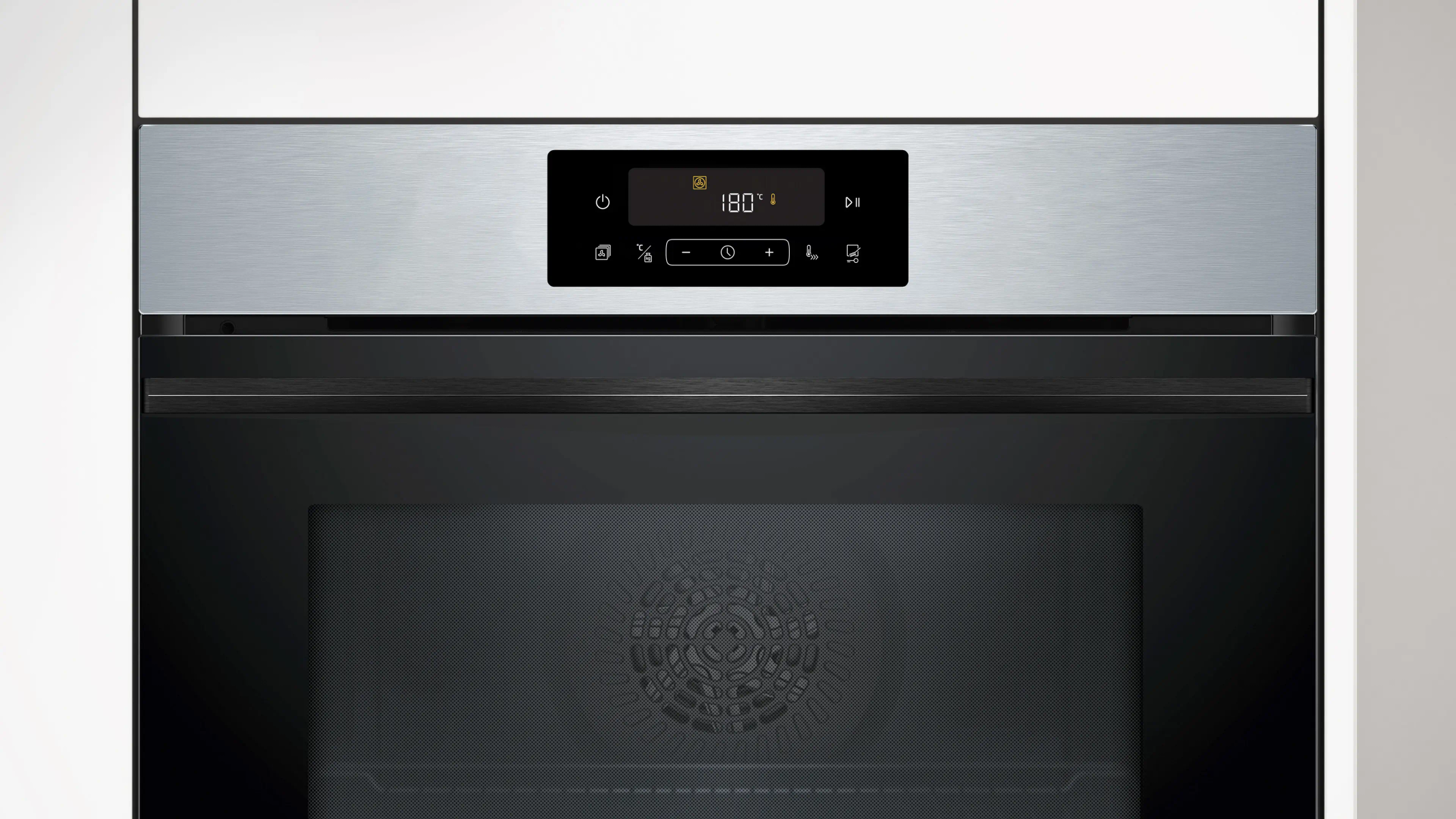 Primer plano de un horno moderno. Tiene una pantalla digital que muestra 180 grados. La puerta del horno es negra con la parte superior metálica.
