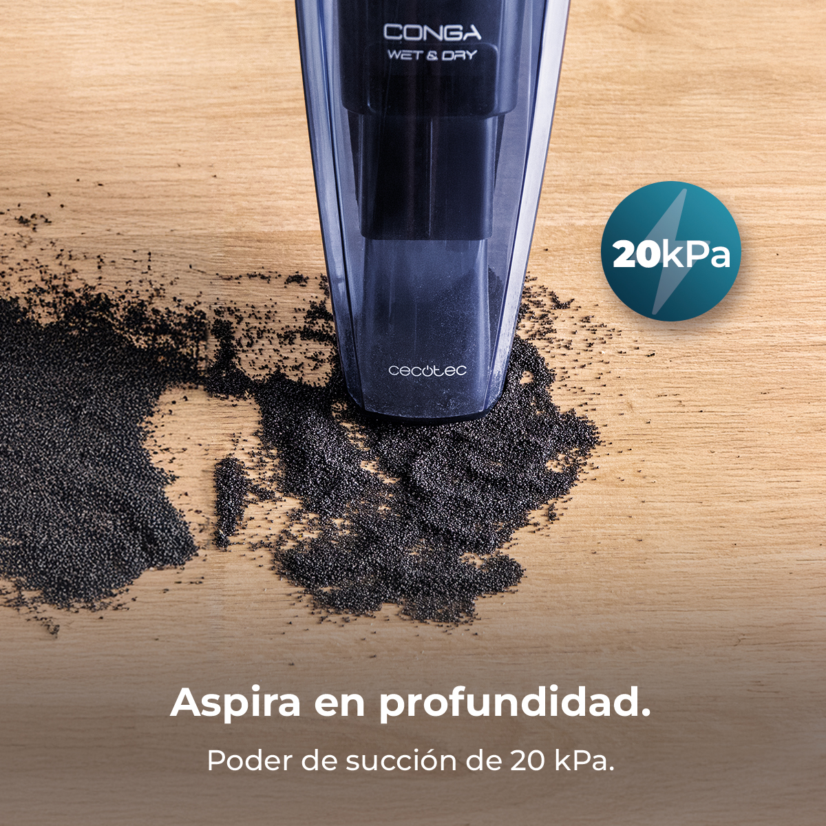 Aspiradora de mano sobre superficie de madera con partículas negras. Texto: 'CONGA Wet & Dry', '20kPa' y poder de succión.