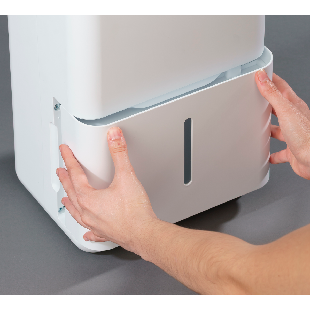 Le mani assemblano un dispositivo bianco con un pannello grigio. Sul pannello è presente una fessura verticale.