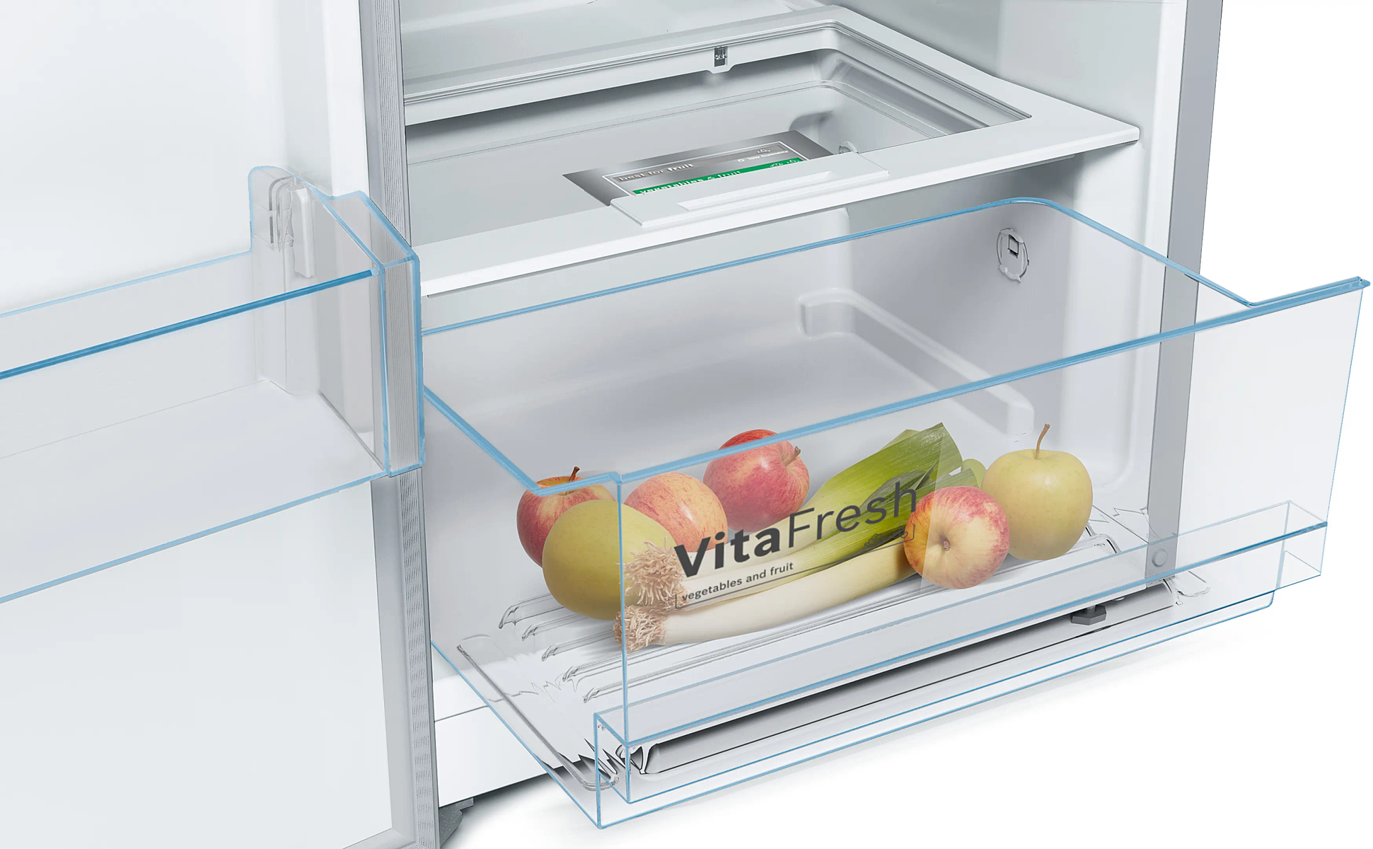 Nevera abierta con frutas y verduras en un cajón transparente. Se ven manzanas y puerros.