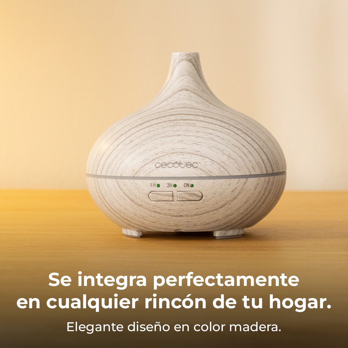 Un difusor de madera blanca y gris está sobre una mesa de madera. Tiene botones y la marca 'cecotec'. El fondo es beige.