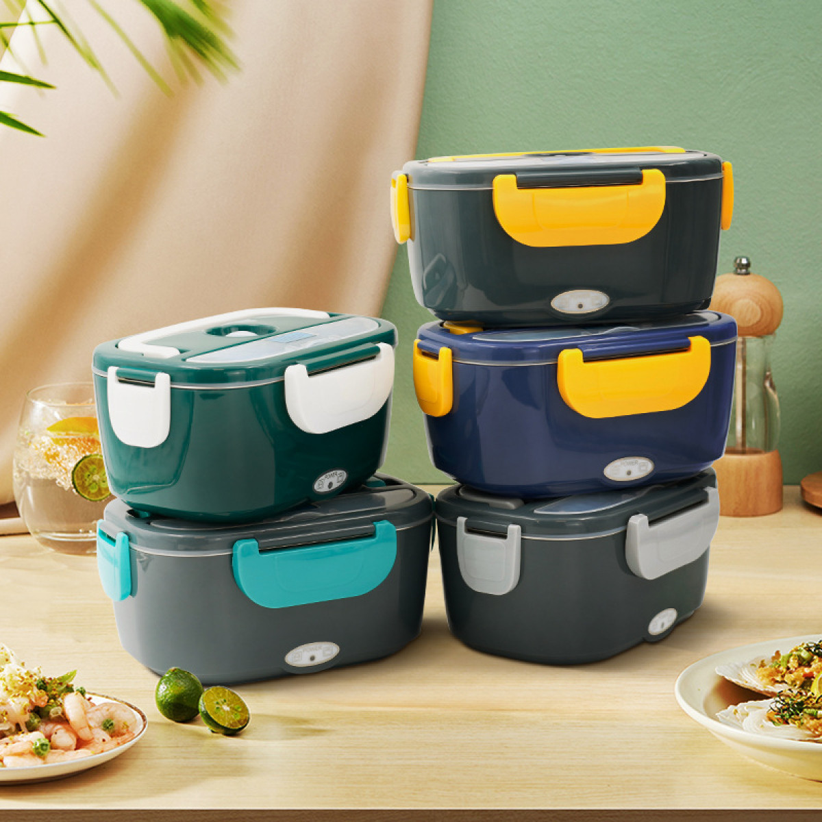 Pięć ułożonych w stos pudełek na lunch w różnych kolorach. Jedzenie i napoje na drewnianej powierzchni. Zielona ściana w tle.