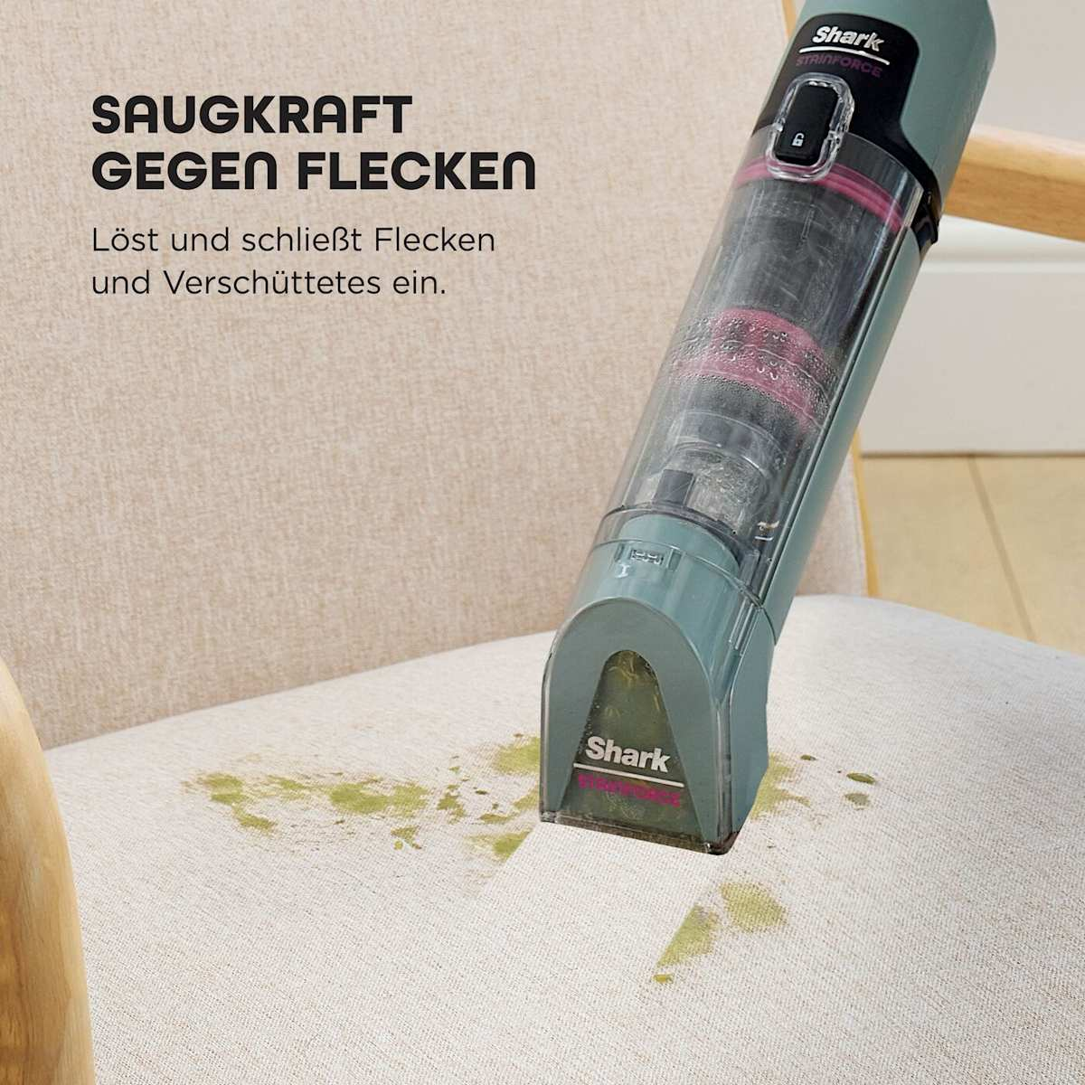 Ein Shark-Staubsauger reinigt einen fleckigen beigen Stuhl. Grüne Flecken sind auf dem Stuhl. Der Staubsauger ist blaugrün und schwarz.