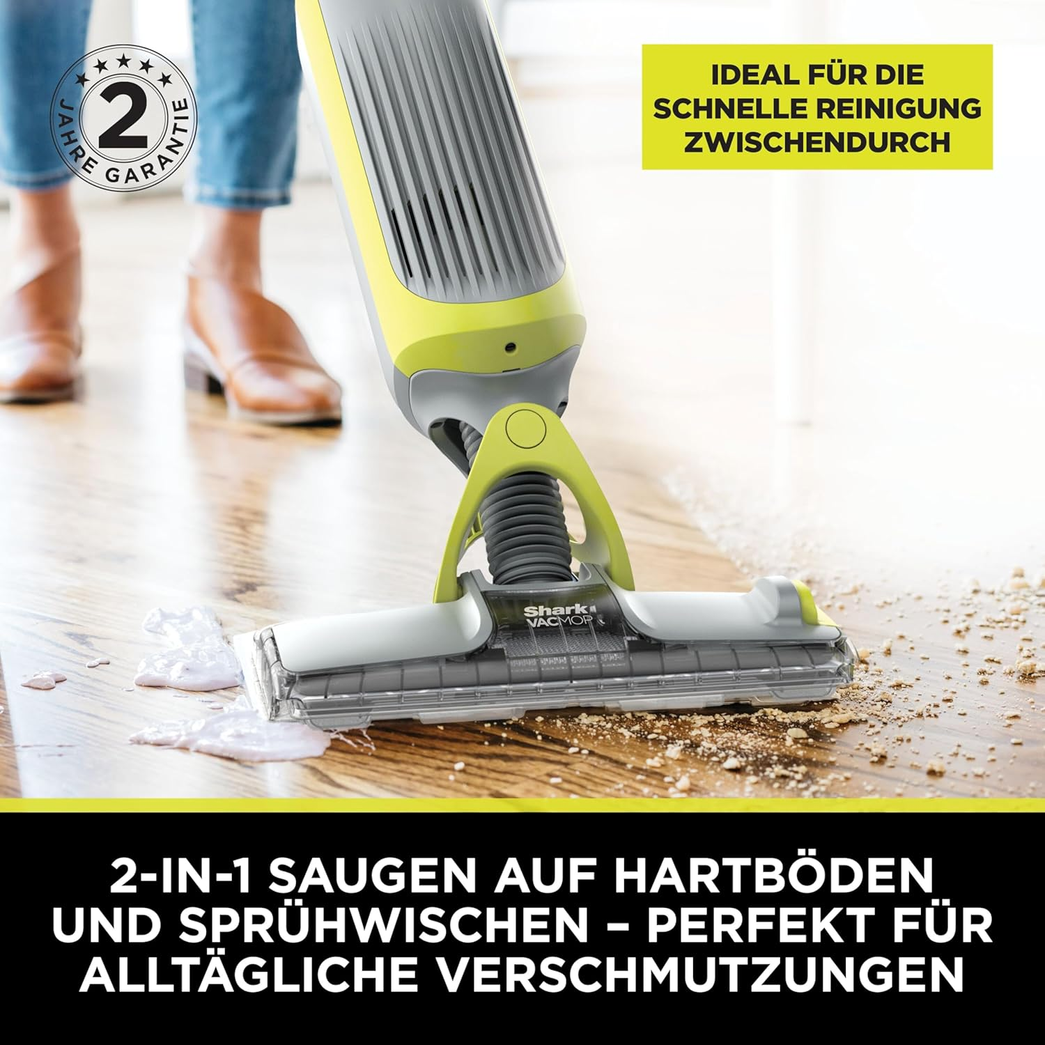Ein gelb-grauer Bodenreiniger reinigt einen Holzboden. Der Reiniger befindet sich vor den Beinen einer Person. Der Text lautet 2-in-1-Reinigung.