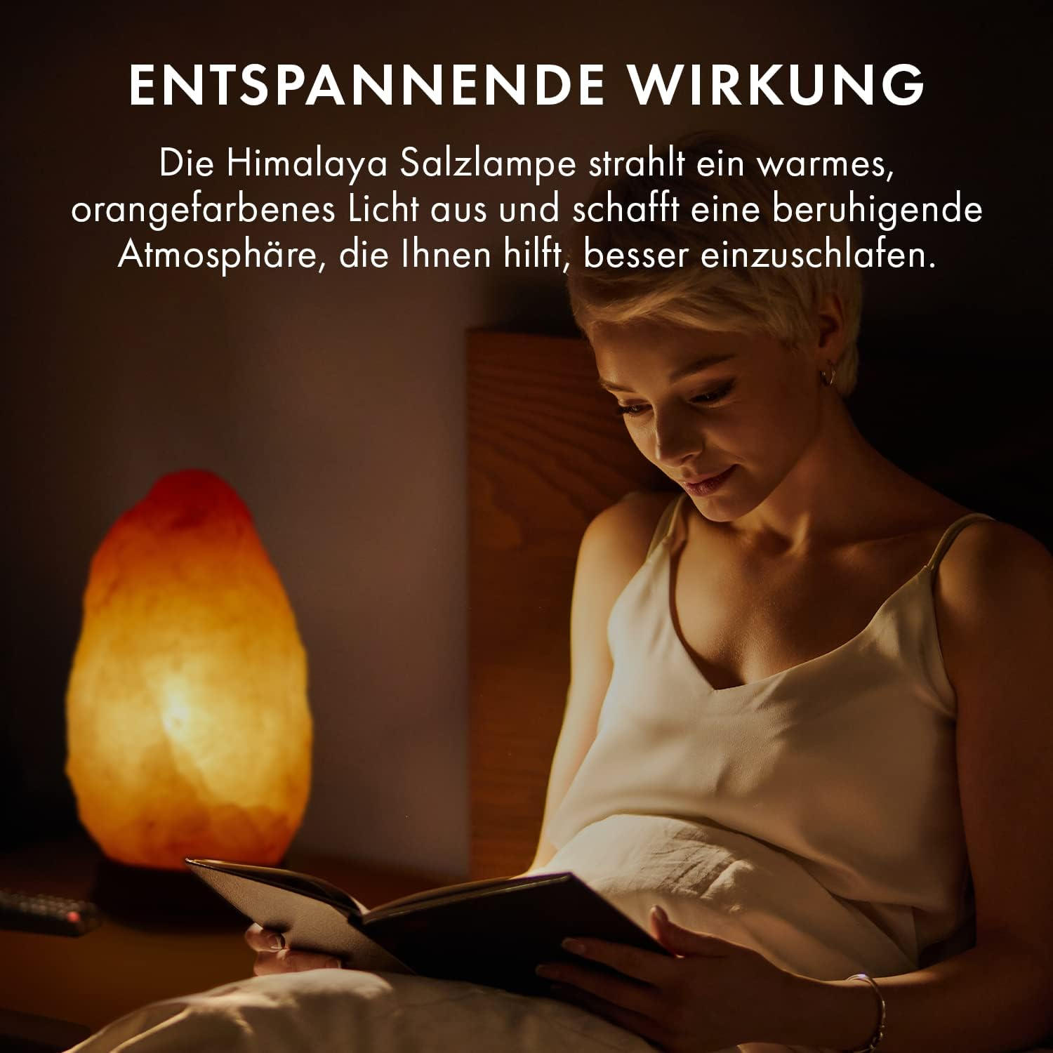 Frau liest mit einer Himalaya-Salzlampe. Die Lampe gibt warmes Licht ab und schafft eine entspannte Atmosphäre.