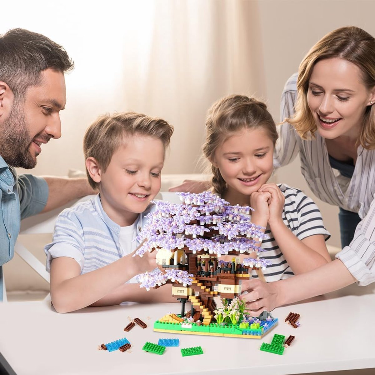 Familie baut ein Baumhausmodell. Vater, Mutter und zwei Kinder lächeln. Das Modell hat lila Blätter und einen braunen Stamm.