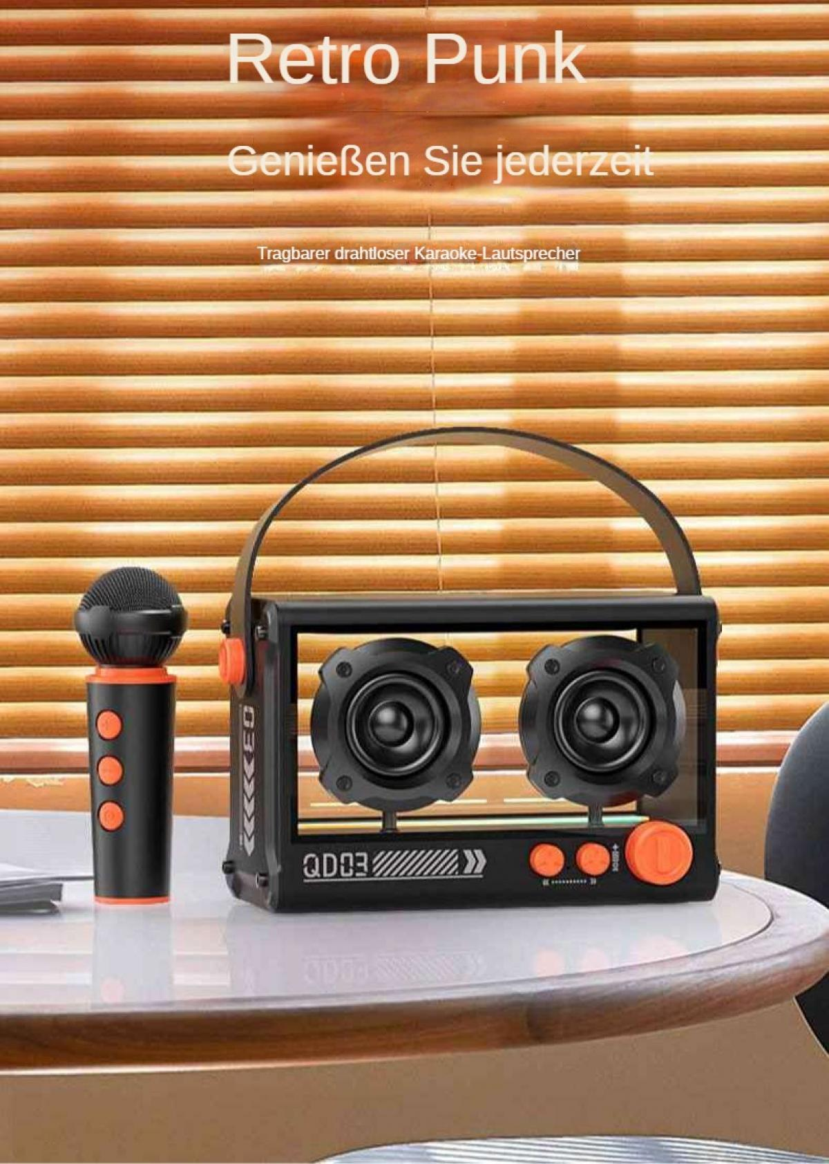 Ein Karaoke-Lautsprecher und Mikrofon stehen auf einem Tisch. Der Lautsprecher ist schwarz, orange und transparent. Der Hintergrund ist ein Holzrollo.