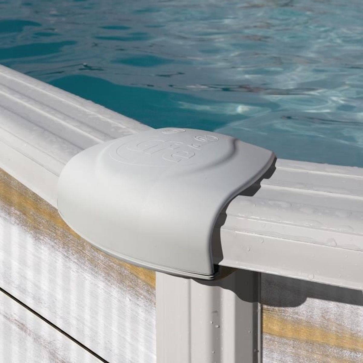 Vista de cerca del borde de una piscina. Una cubierta de plástico gris se asienta sobre el borde blanco de la piscina, con agua visible al fondo.