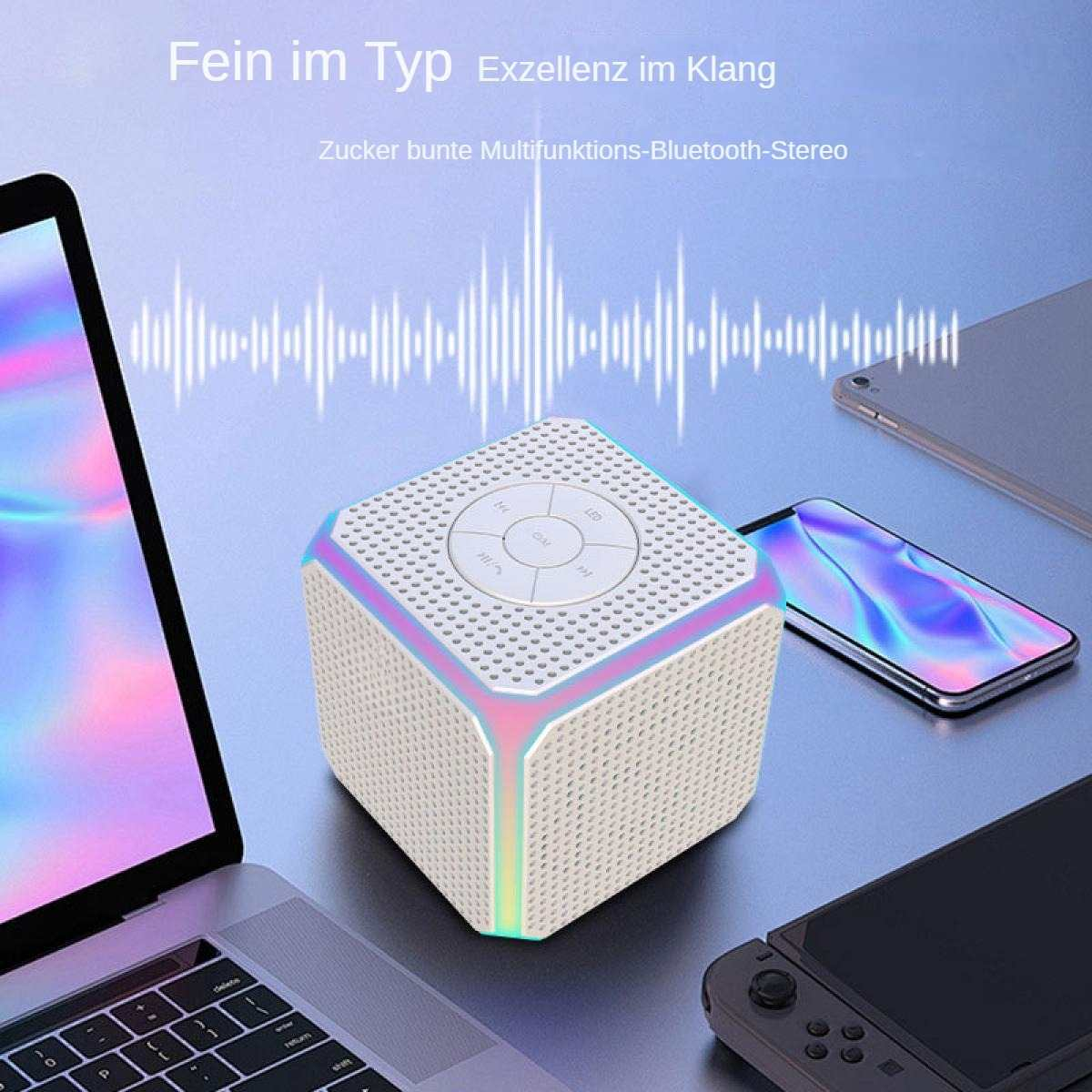 Ein weißer Lautsprecher mit Regenbogenakzenten steht auf einem Tisch, umgeben von elektronischen Geräten.