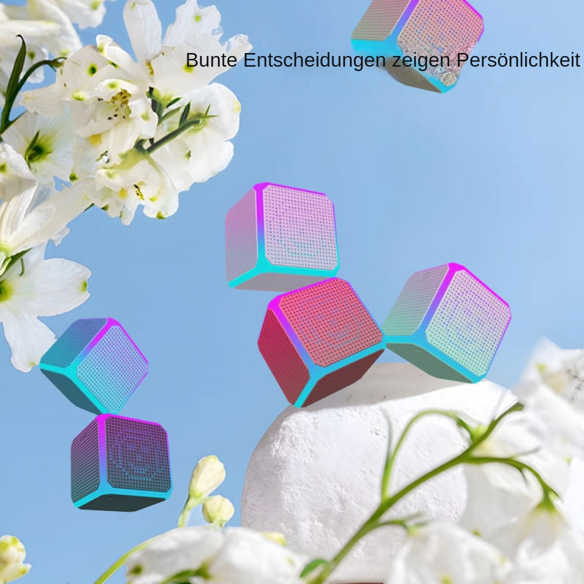 Bunte Würfel-Lautsprecher schweben in der Nähe weißer Blumen vor blauem Himmel. Text auf Deutsch: Bunte Entscheidungen zeigen Persönlichkeit.