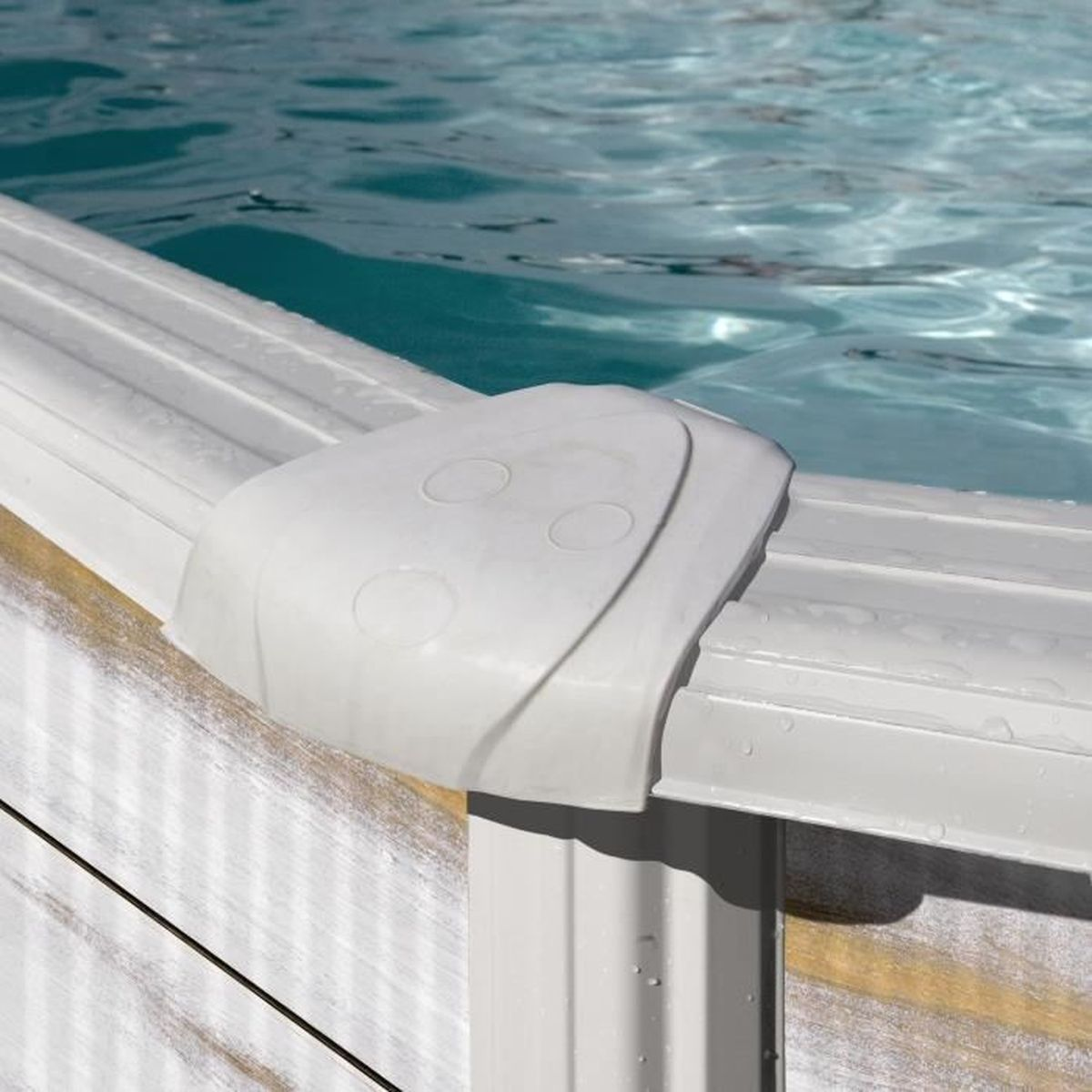 Vista de cerca del borde de una piscina. Esquina de plástico blanco, agua y paneles de madera. El agua es turquesa y ondulada.