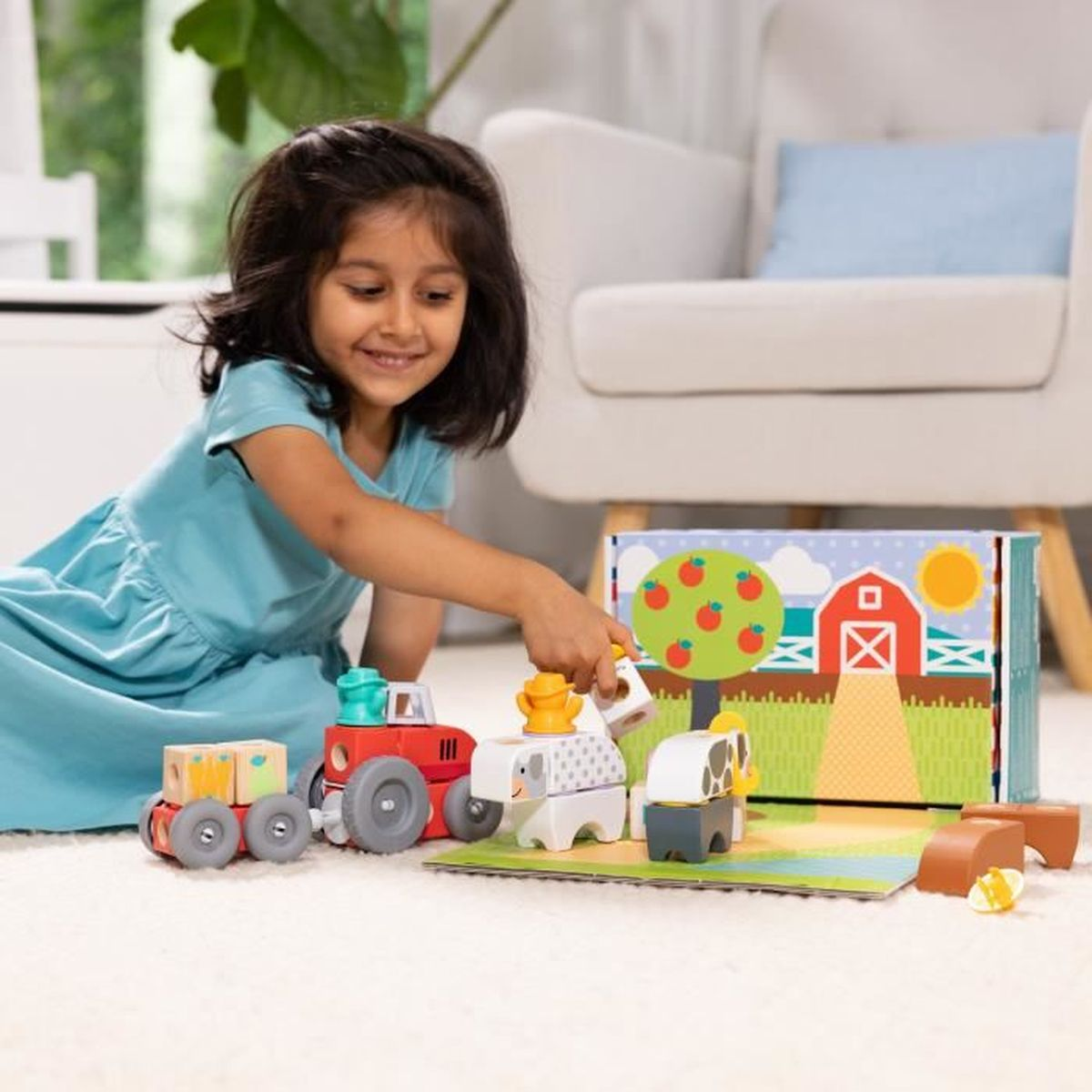 Una niña juega con un juego de juguetes de granja. Incluye un tractor, animales y un telón de fondo de una escena de granja. Sonríe.