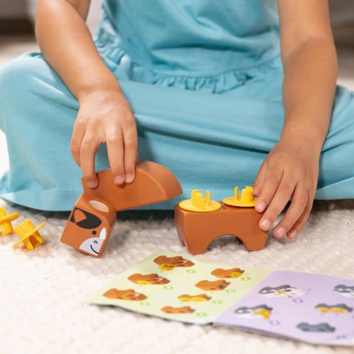 Un niño en azul juega con piezas de rompecabezas de animales de madera. Un libro con imágenes de animales está frente a ellos.