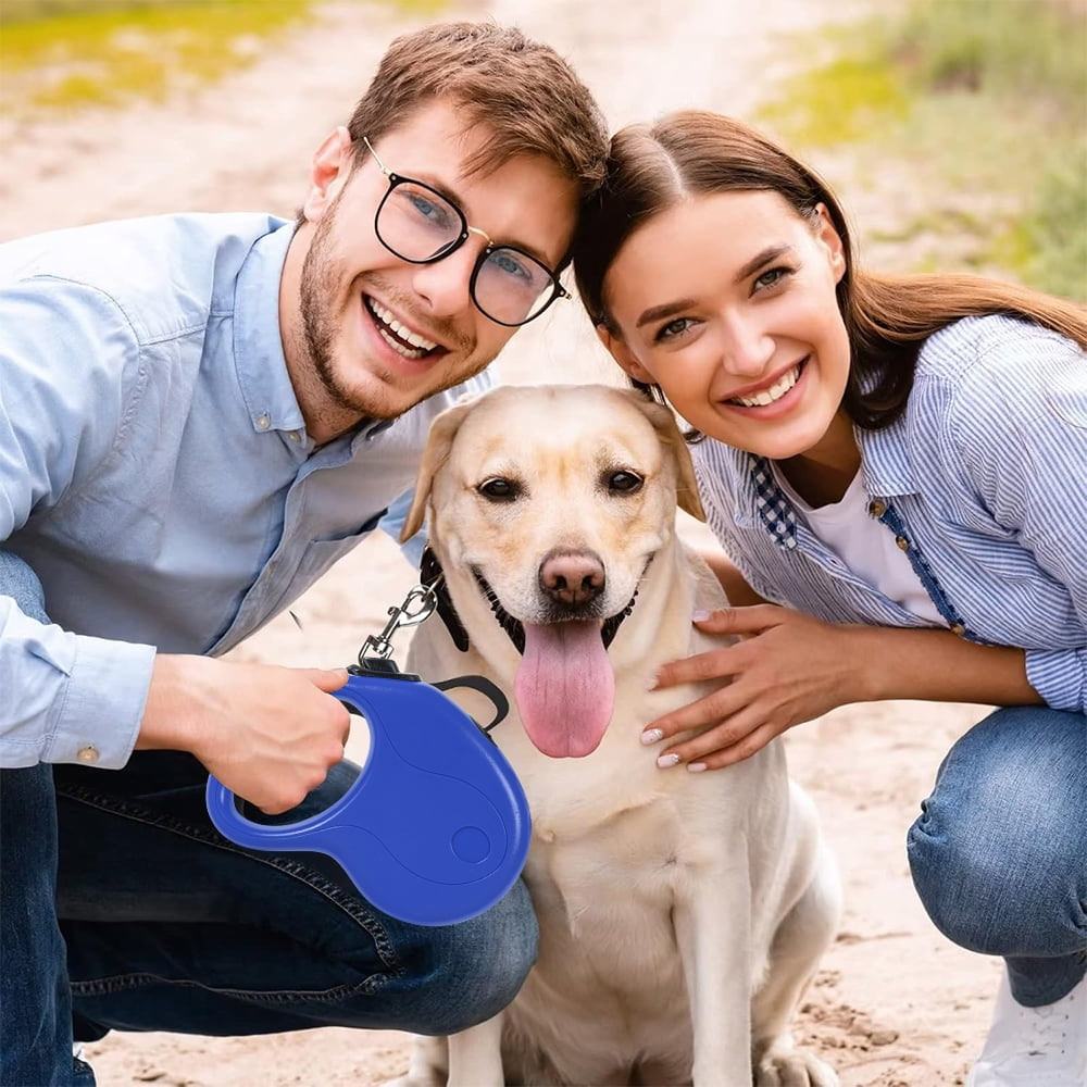 Ein Paar lächelt mit einem Hund. Der Mann hält eine blaue Leine. Der Hund hat die Zunge draußen. Die Frau berührt den Hund.