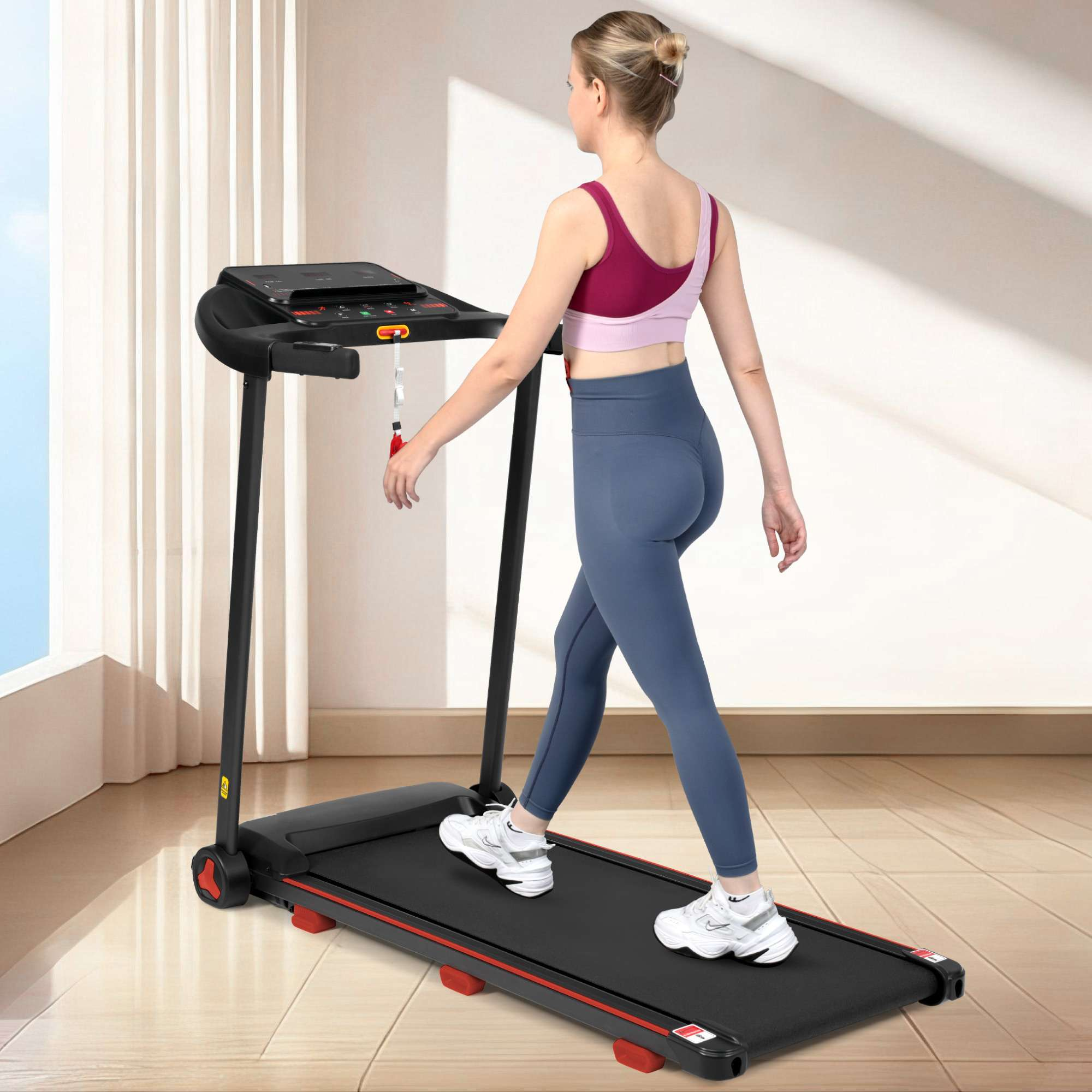 Eine Frau geht auf einem Laufband. Sie trägt ein rosa-lila Oberteil und blaue Leggings. Das Laufband ist schwarz.