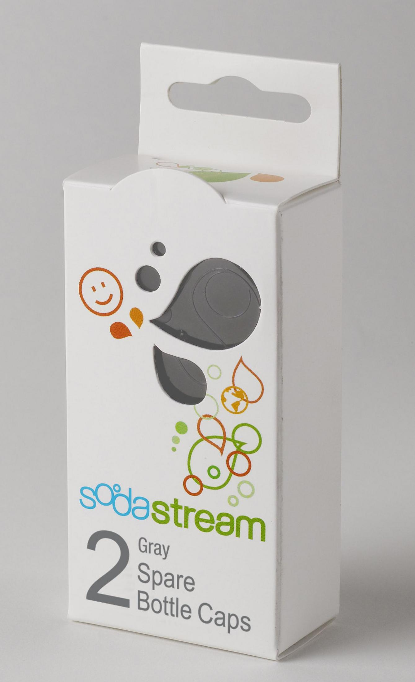 Eine weiße Schachtel mit 'sodastream'-Logo und '2 Graue Ersatzflaschendeckel'-Text. Sie hat bunte Grafiken und einen Griff.