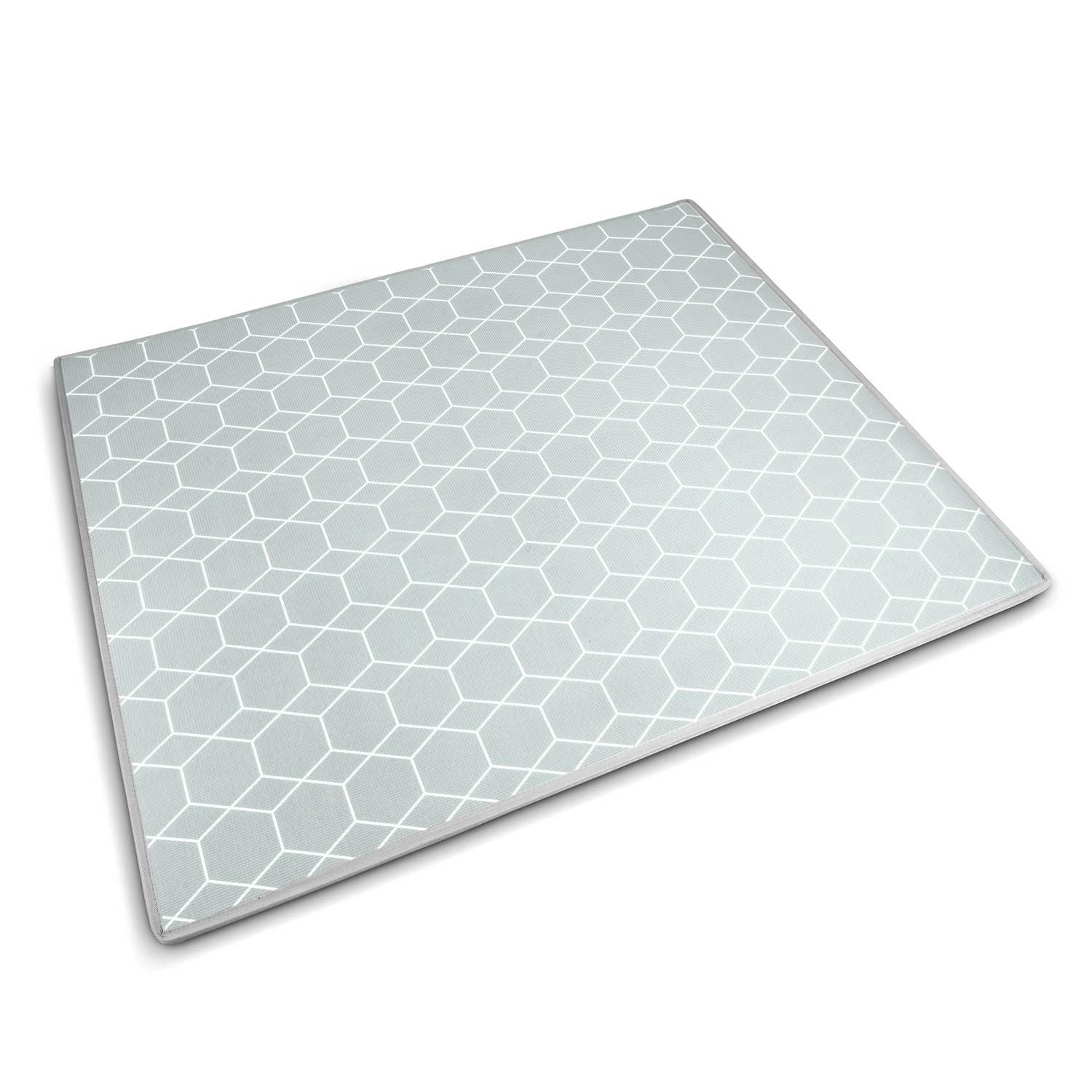 Una estera rectangular con superficie gris azulado pálido y patrón geométrico blanco. Tiene un borde blanco y está sobre una superficie blanca.