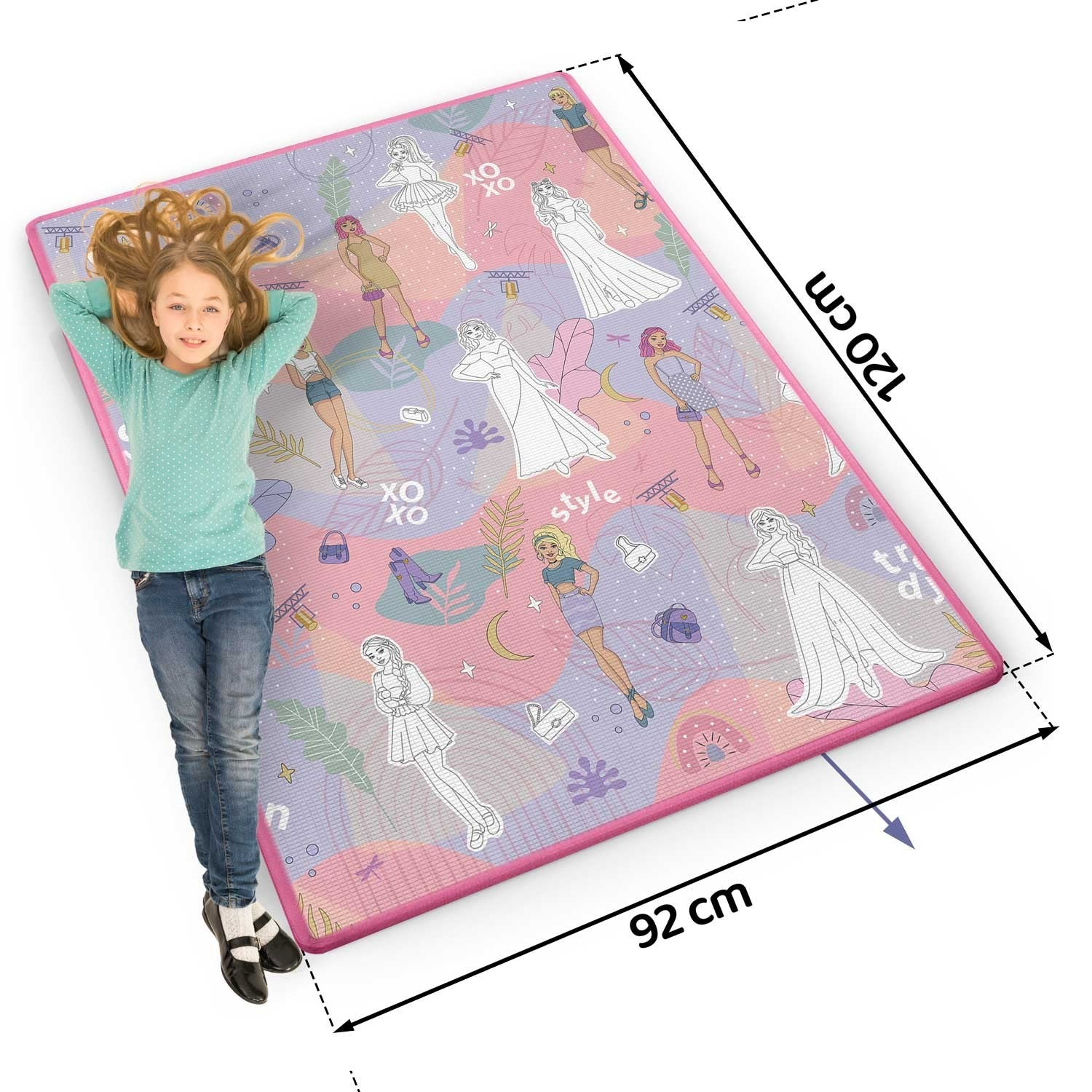 Una niña yace sobre una alfombra estampada con ilustraciones de moda. La alfombra tiene un borde rosa. Se indican las dimensiones 120x92 cm.