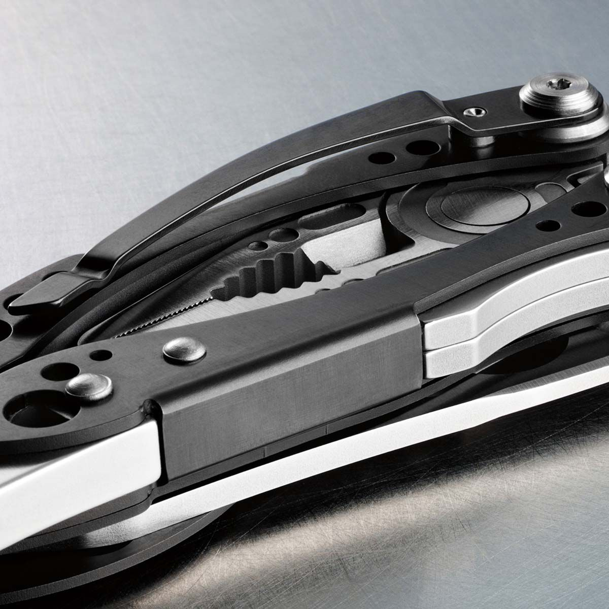 Nahaufnahme eines Multitools. Es ist silber und schwarz mit verschiedenen Werkzeugen, darunter eine Säge, ein Messer und ein Schraubendreher. Der Hintergrund ist metallisch.