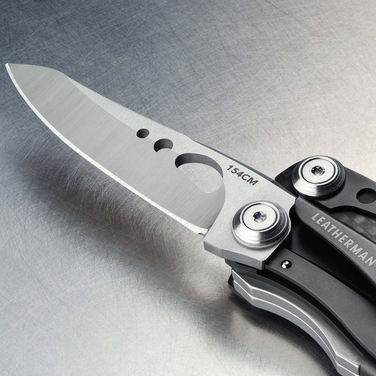 Nahaufnahme eines Leatherman Multi-Tool-Messers auf einer Metalloberfläche. Die Klinge ist geöffnet, mit dem Text '154CM'.