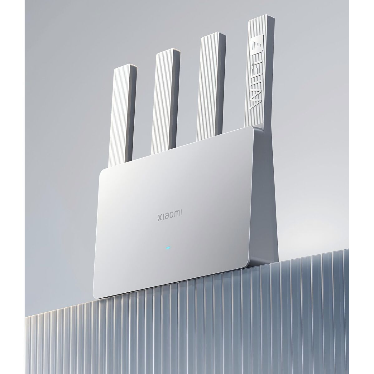 Un router Xiaomi bianco è su una superficie strutturata. Ha quattro antenne e il logo del marchio è visibile. Lo sfondo è grigio chiaro.