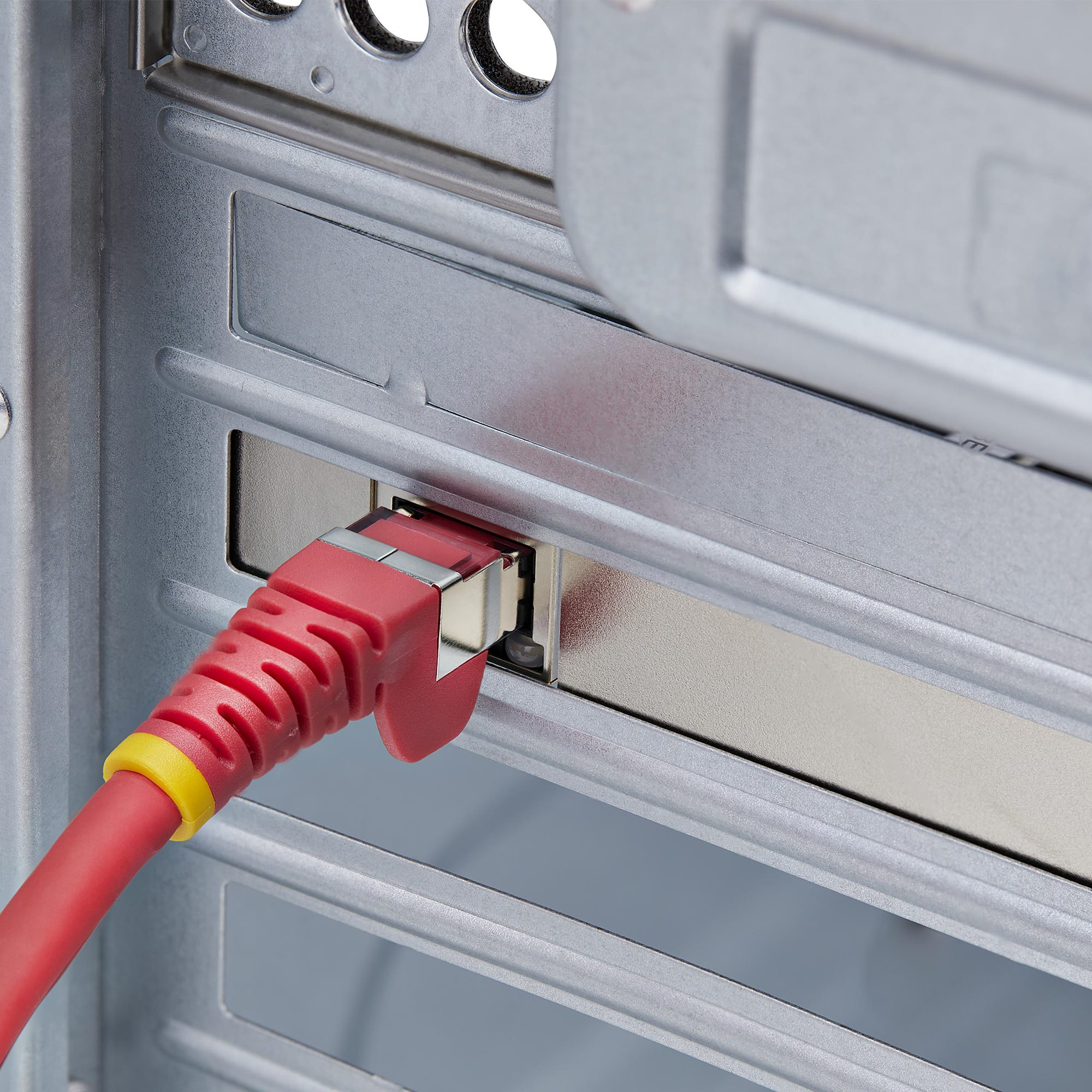 Ein rotes Ethernet-Kabel ist in ein Computergehäuse eingesteckt. Das Kabel hat einen gelben Ring.