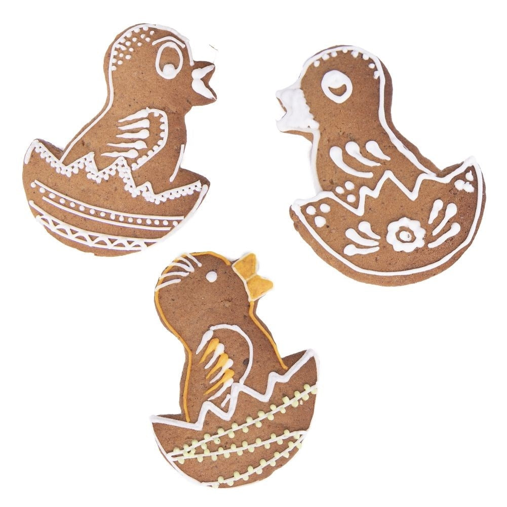 Tres pollitos de jengibre sobre fondo blanco. Cada pollito es marrón con detalles de glaseado blanco y amarillo, en varias poses.