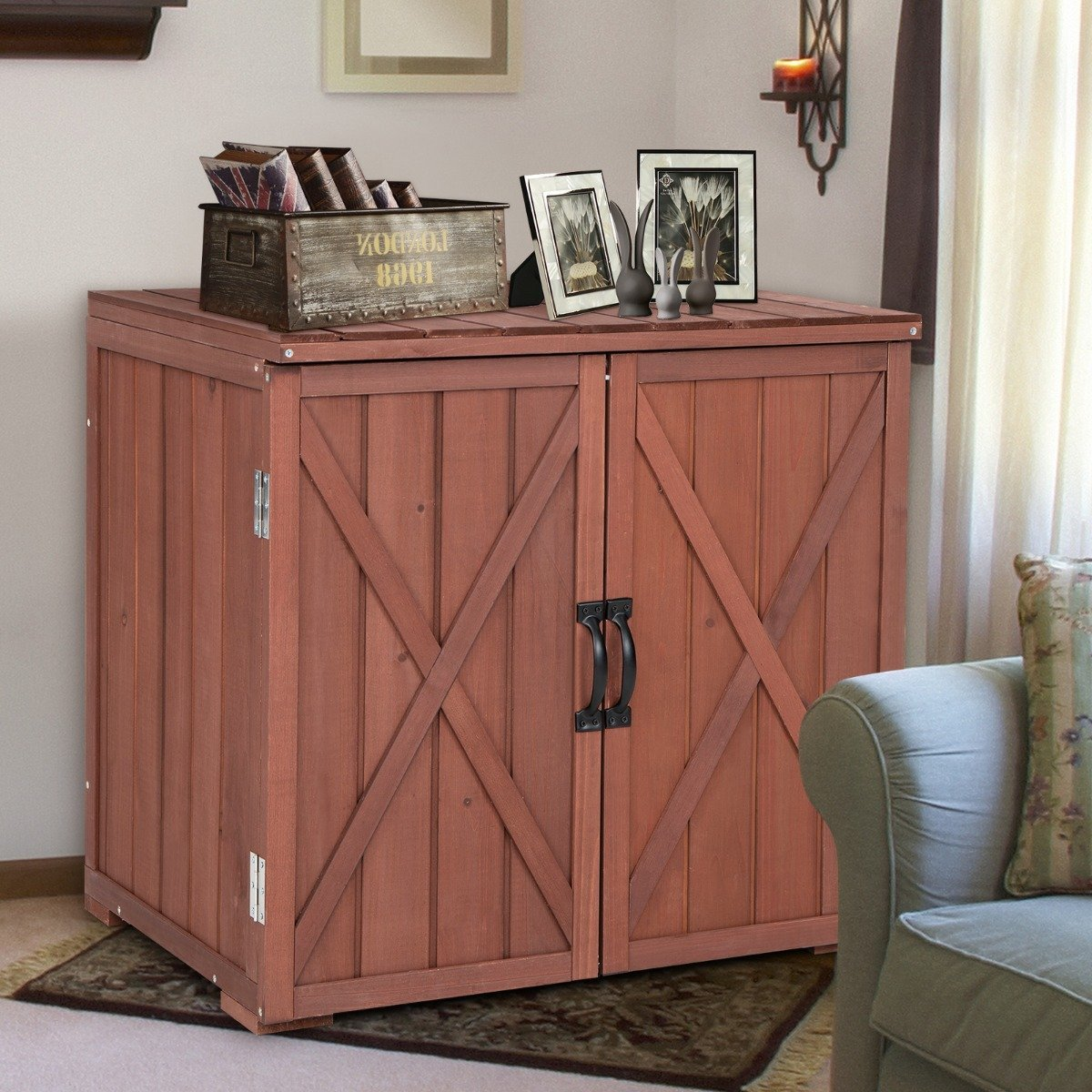 Gabinete de madera con puertas de diseño cruzado. Encima, una caja, marcos y figuras de conejos. Fondo: pared, candelabro y cortinas.