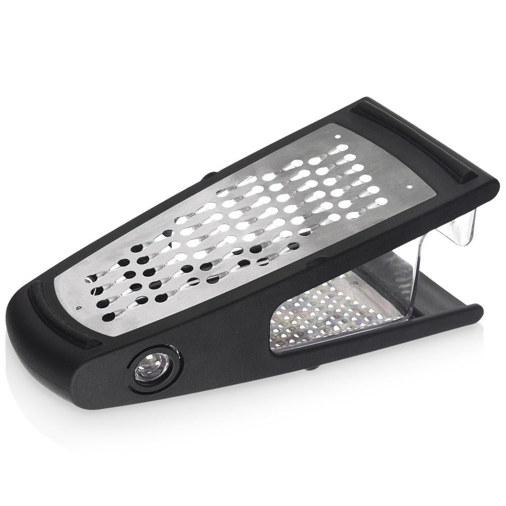 Un rallador negro y plateado, en ángulo sobre una superficie blanca. Tiene un diseño rectangular con un contenedor de plástico transparente.