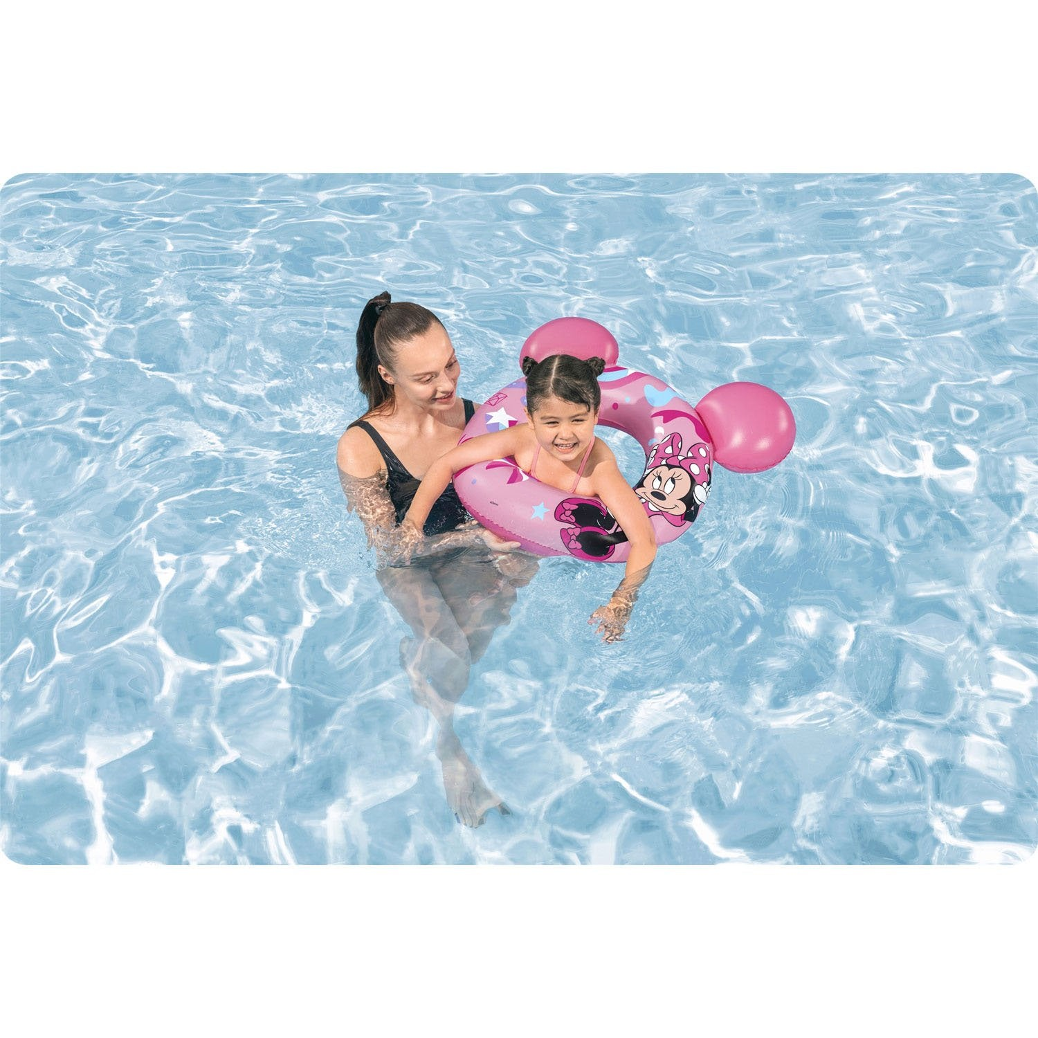 Una mujer y un niño están en una piscina. El niño está en un flotador rosa de Minnie Mouse. La mujer sostiene al niño.